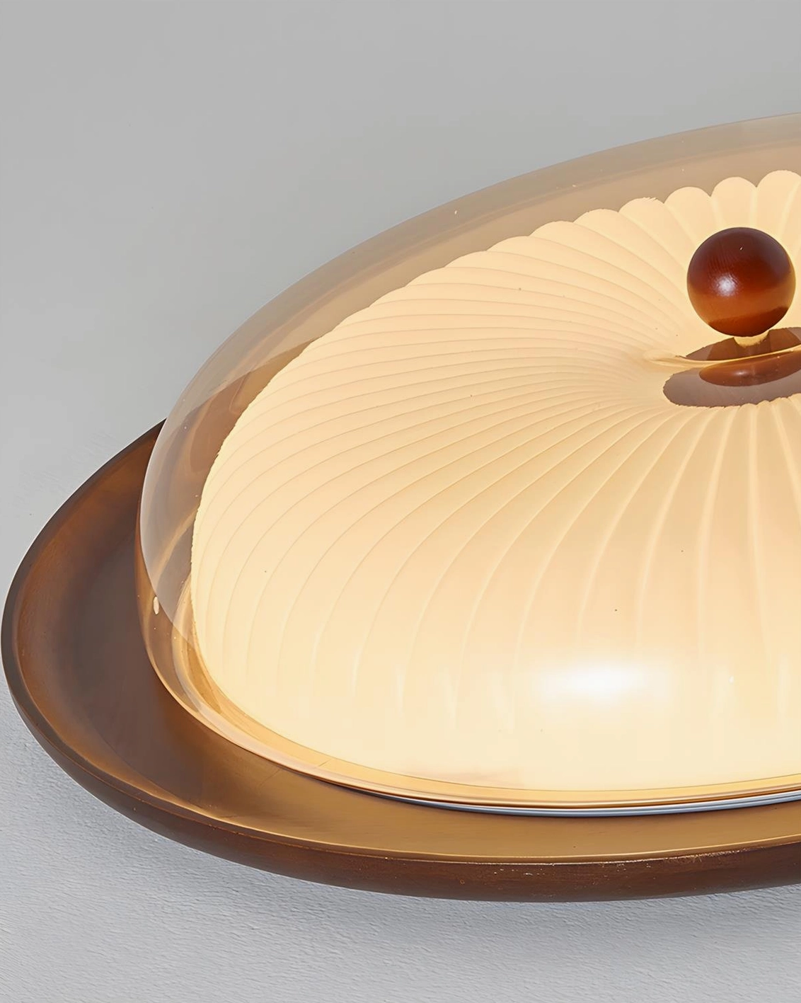 Crestfold ceiling lamp low-angle side detail showing textured ribbed frosted glass dome, smooth walnut wood base and wooden finial
