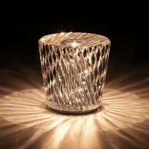 Crystal diamond table lamp emitting warm 3000K light, eye-level view on dark backdrop showing prismatic refraction effect