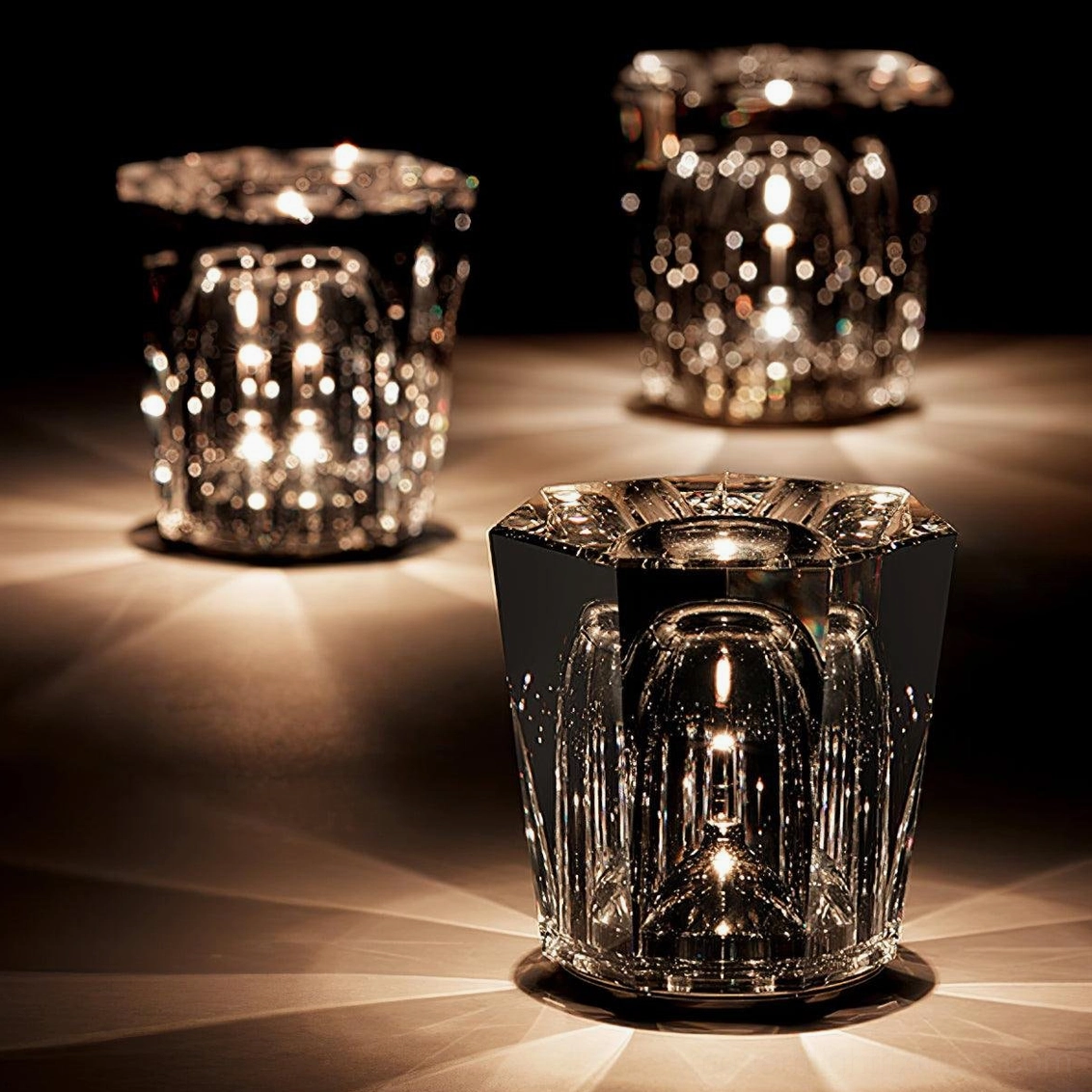 Multiple crystal diamond table lamps displayed together on tabletop, overhead view showing different hand-cut facet designs with ambient warm lighting