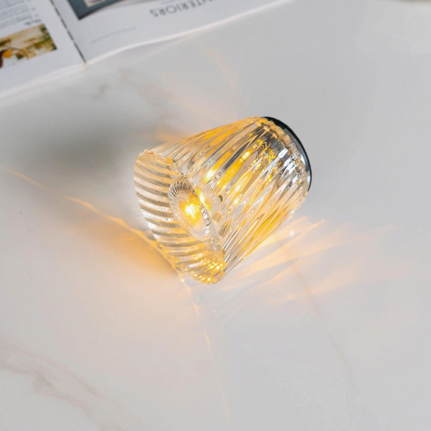 Crystal diamond table lamp warm light ambiance, hand-polished faceted crystal creating prismatic glow effect, contemporary interior