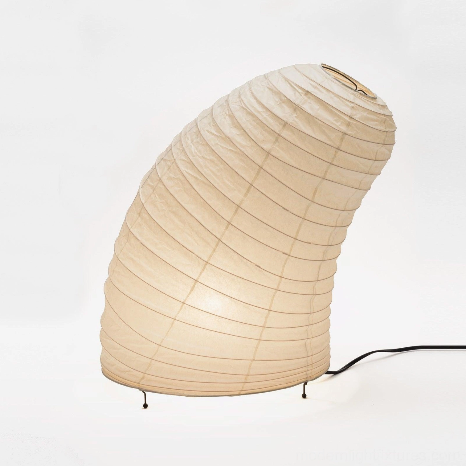 Curved ribbed paper table lamp with off-white shade and minimalist metal support feet, studio view