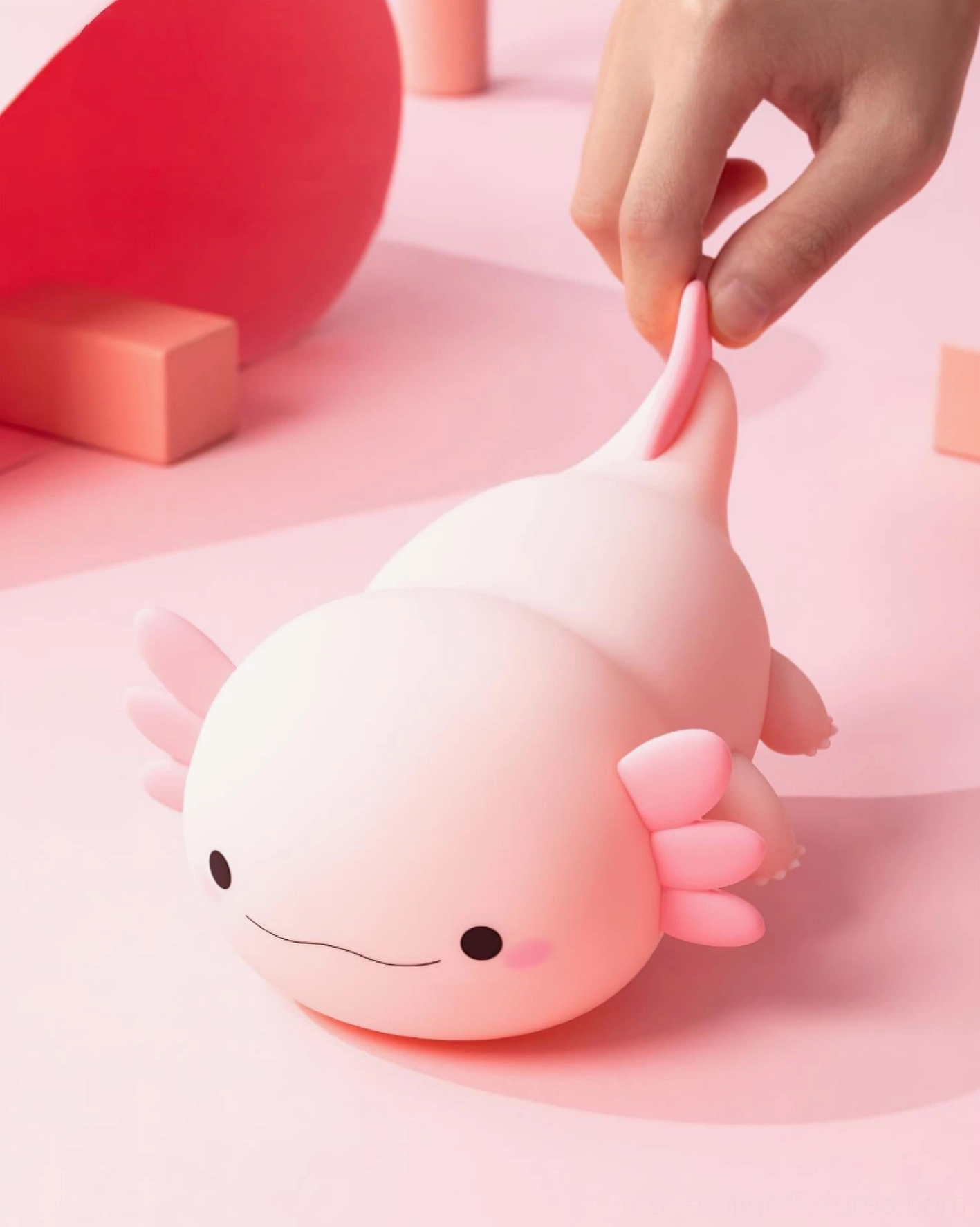 Compact axolotl silicone light fixture on minimalist pink desktop with hand touch interaction