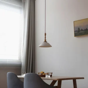 Vintage scalloped pendant light hanging above wooden dining table in minimalist interior setting
