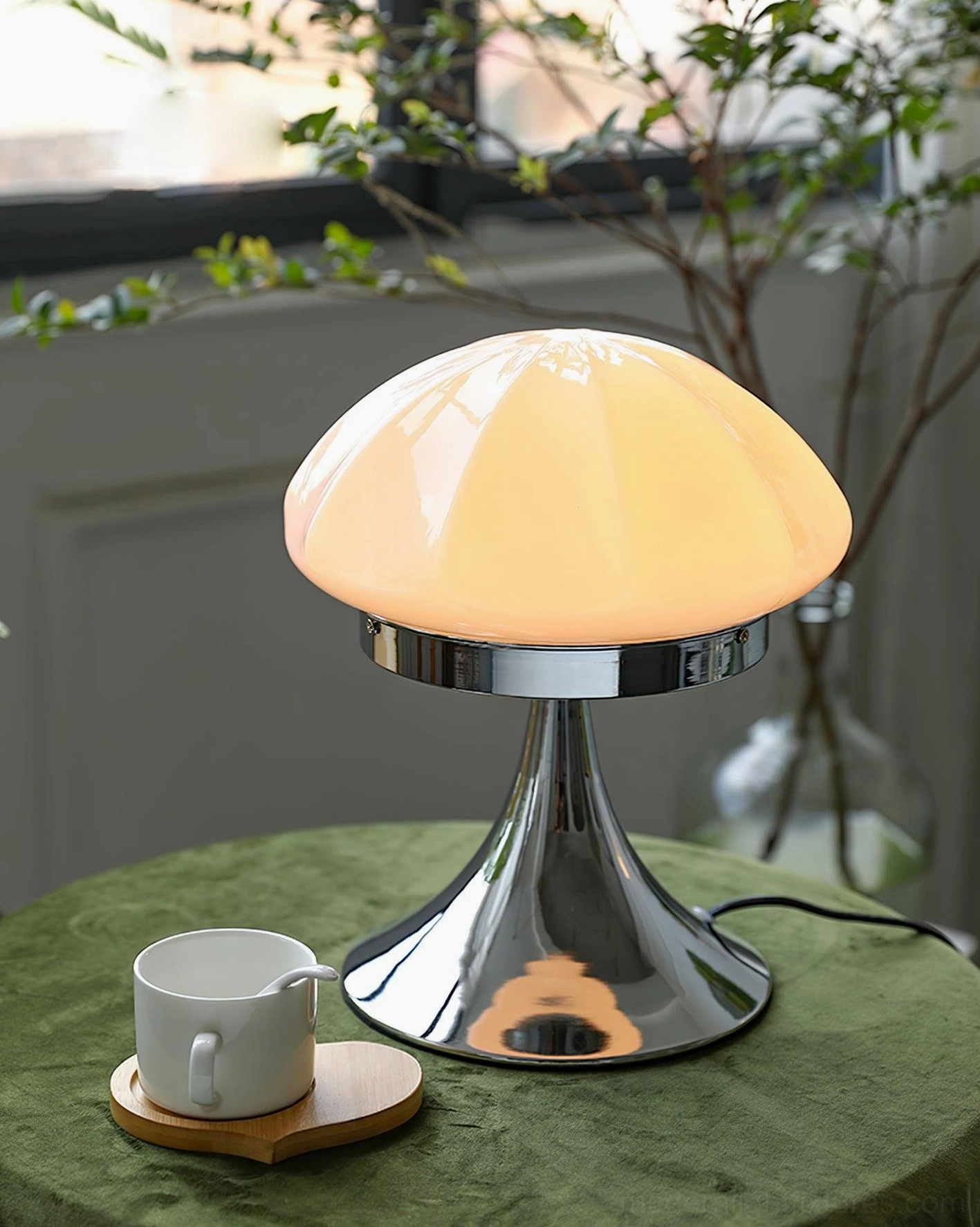 Dario mushroom table lamp with warm beige glass shade on green velvet side table with coffee cup and plants