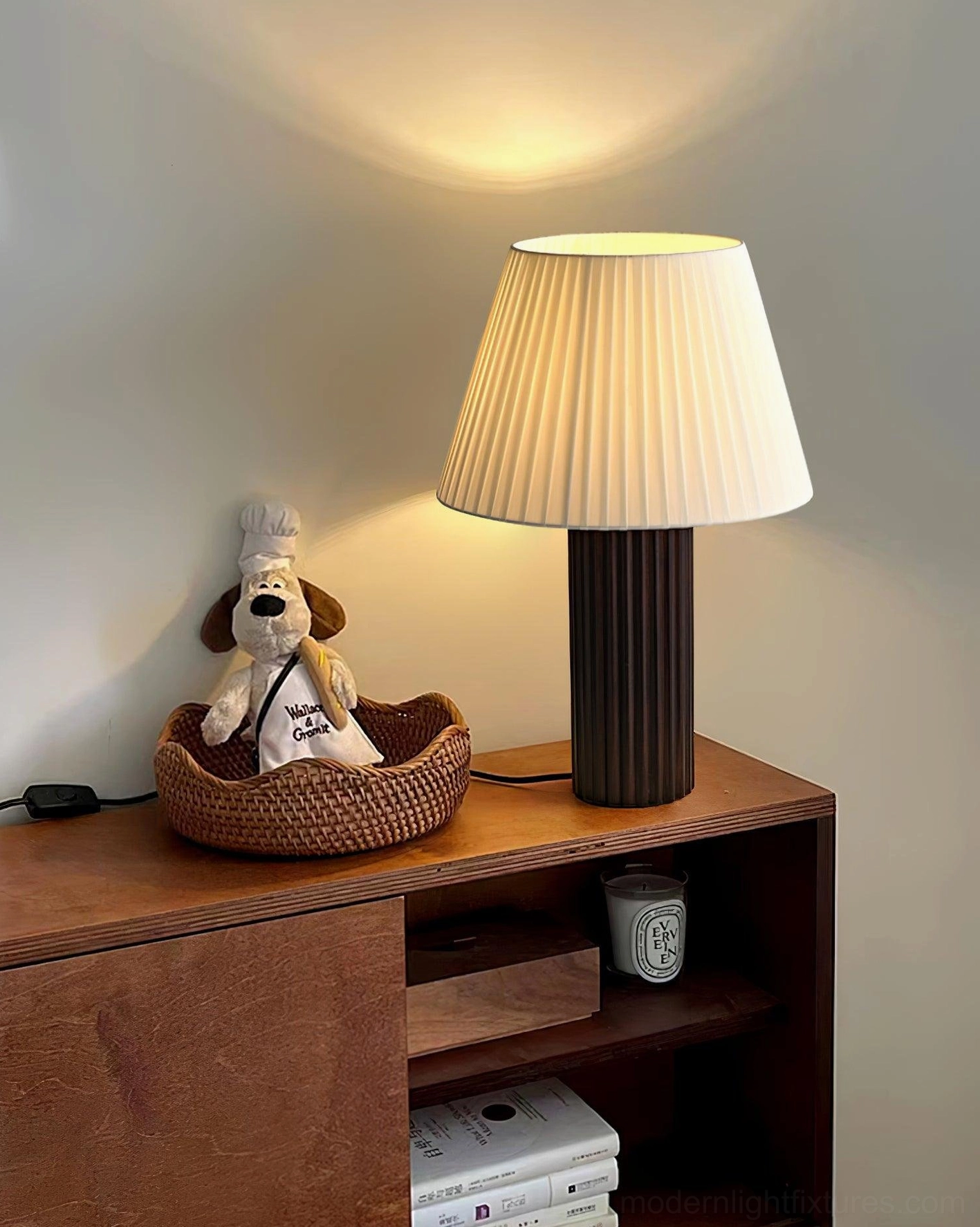 Dark ribbed base table lamp with warm illuminated pleated shade positioned on home storage cabinet with everyday decor in vintage minimalist interior