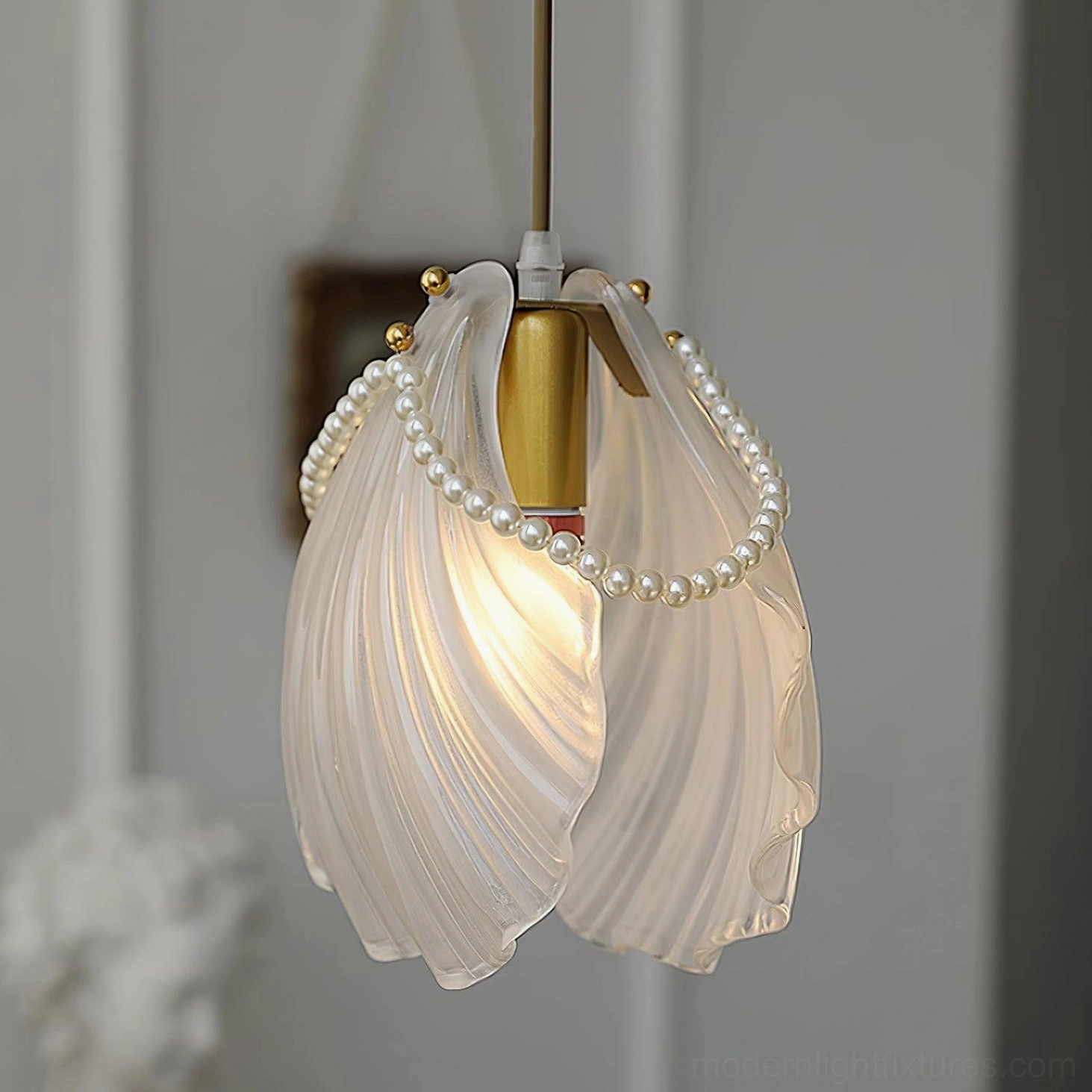 Decorative shell pendant lamp with frosted glass and gold metal hardware in home setting