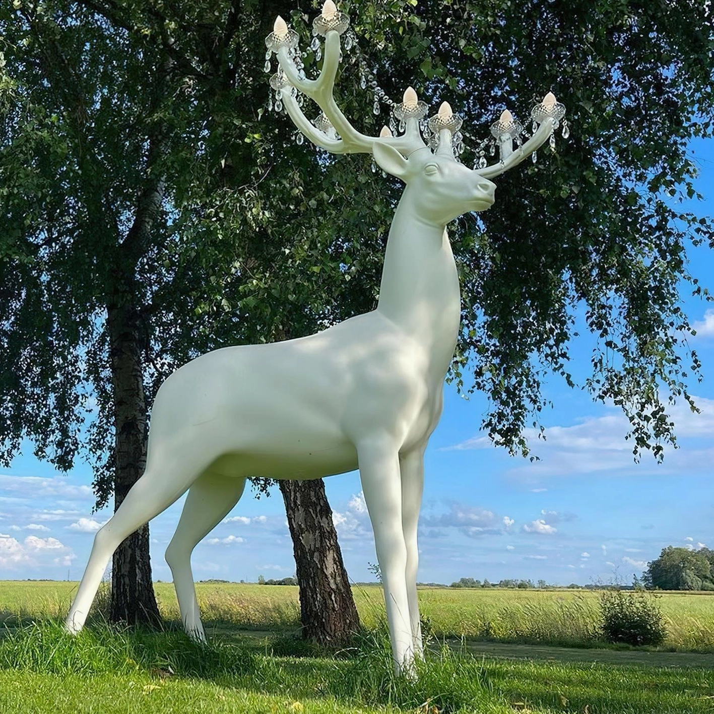 Sculptural deer floor lamp with warm lighting in woodland park outdoor natural setting