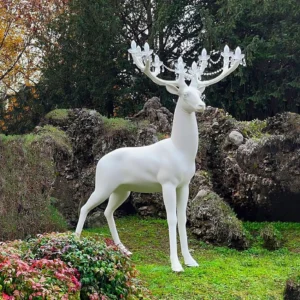Deer floor lamp in outdoor garden setting, front three-quarter view showing sculptural form and chandelier lighting