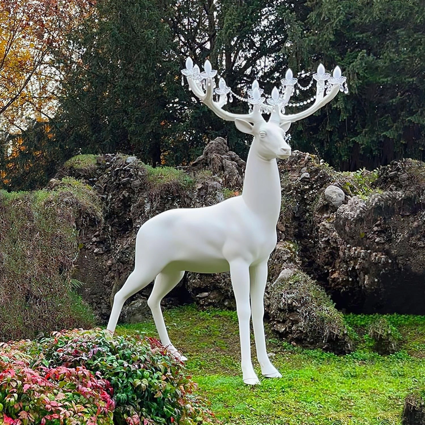Deer floor lamp in outdoor garden setting, front three-quarter view showing sculptural form and chandelier lighting