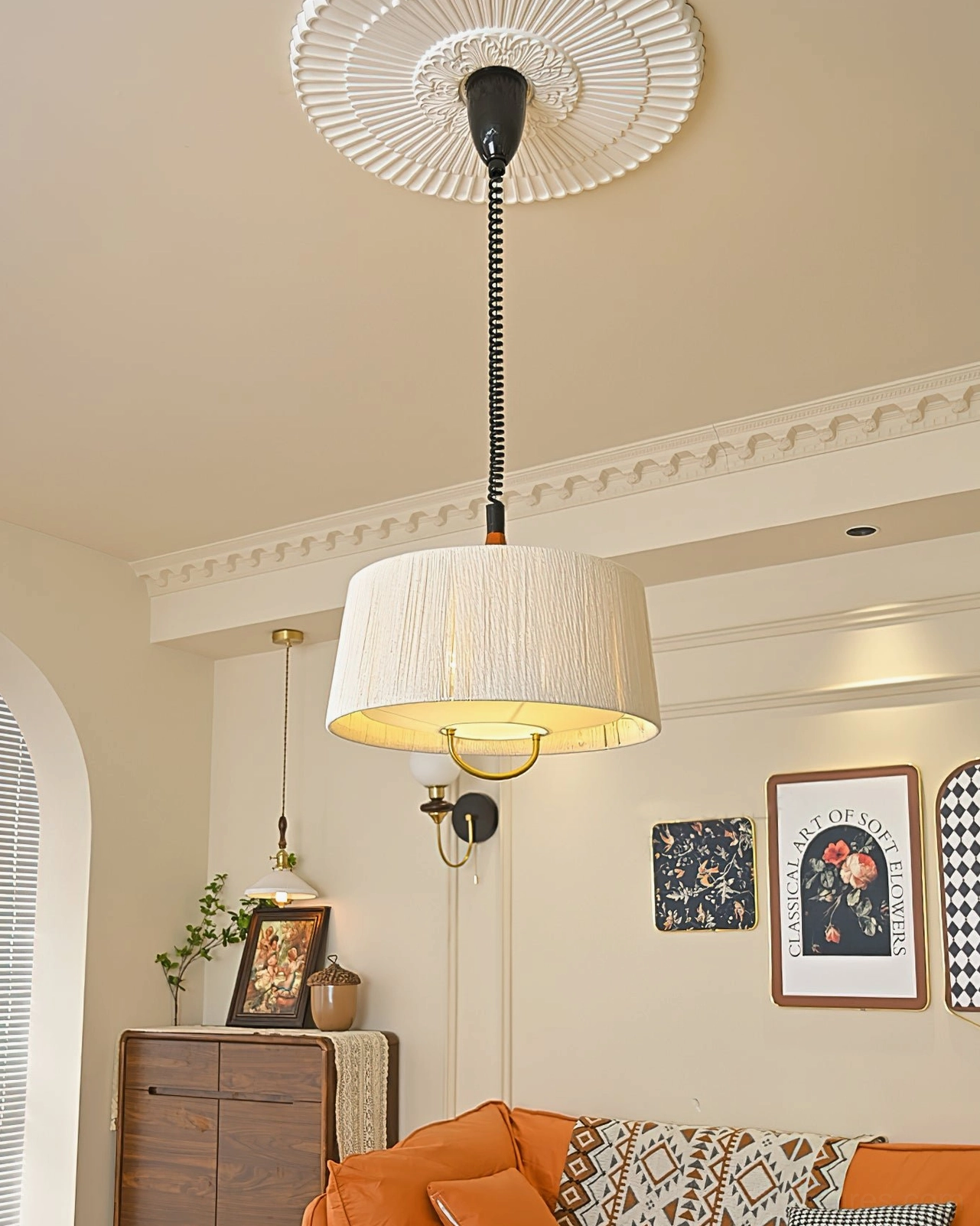 Delaney tapered drum pendant with decorative ceiling rose base, beige pleated fabric shade and gold hardware accents in residential setting