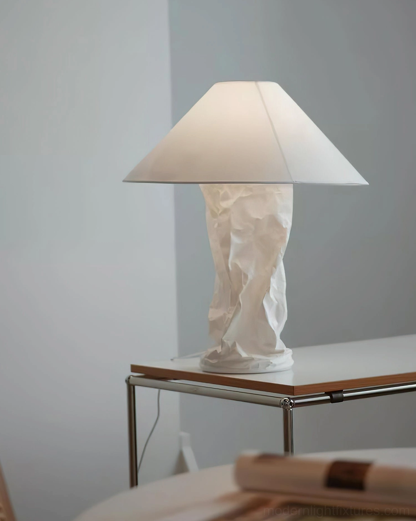 Sculptural crinkled paper table lamp on metal and wooden side table in neutral interior