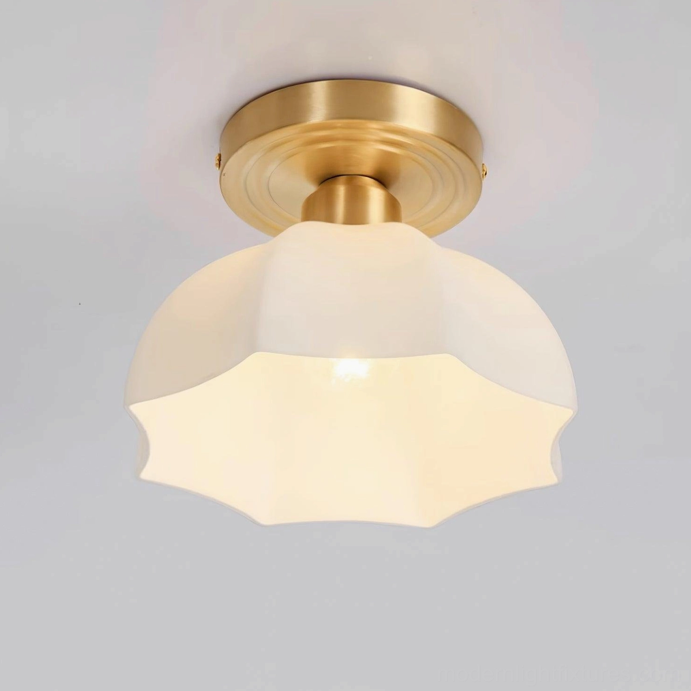 Detailed view of scalloped acrylic shade and brass mounting of semi-flush ceiling light