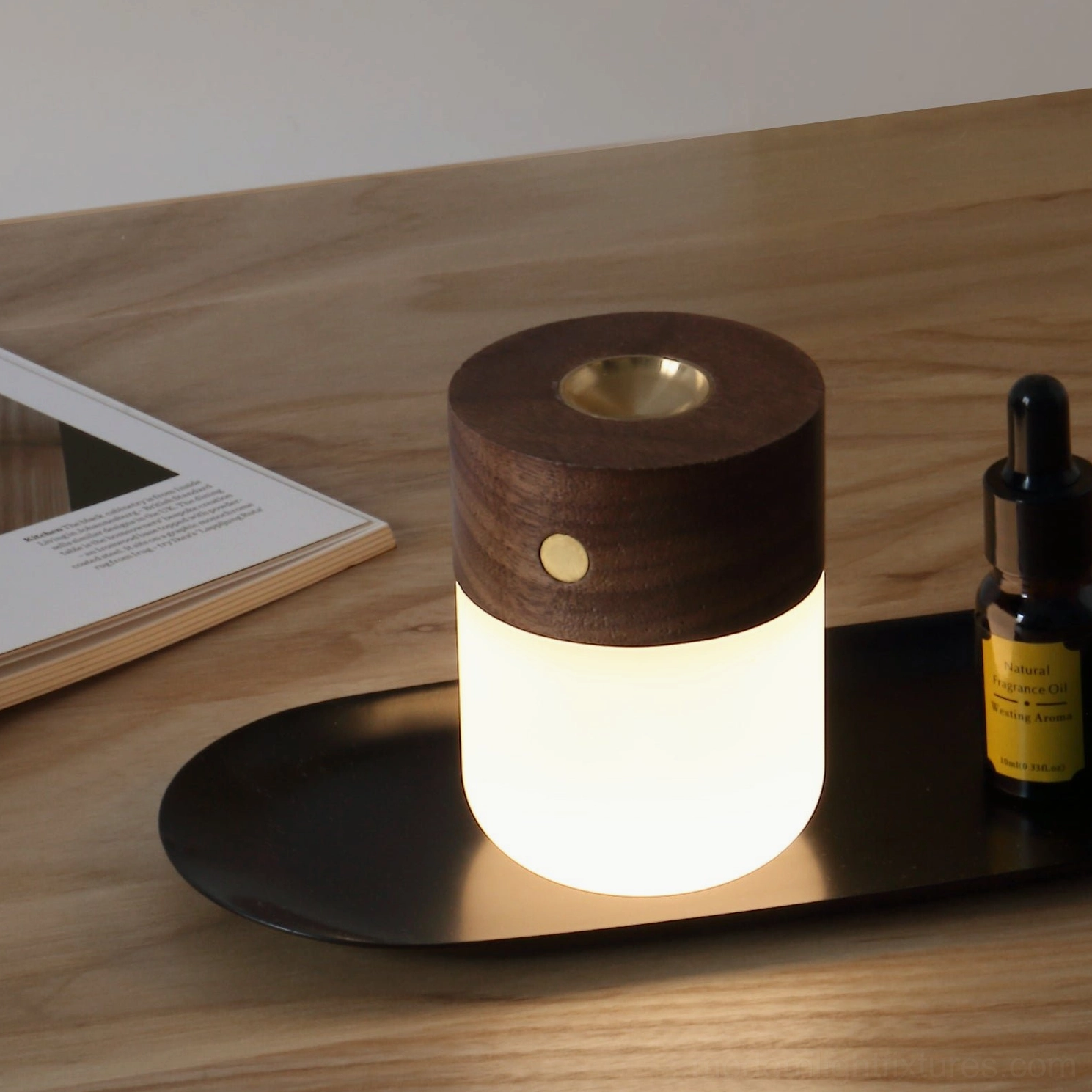 Aroma diffuser table lamp with brass nozzle lit on wooden desk with essential oil and book styling