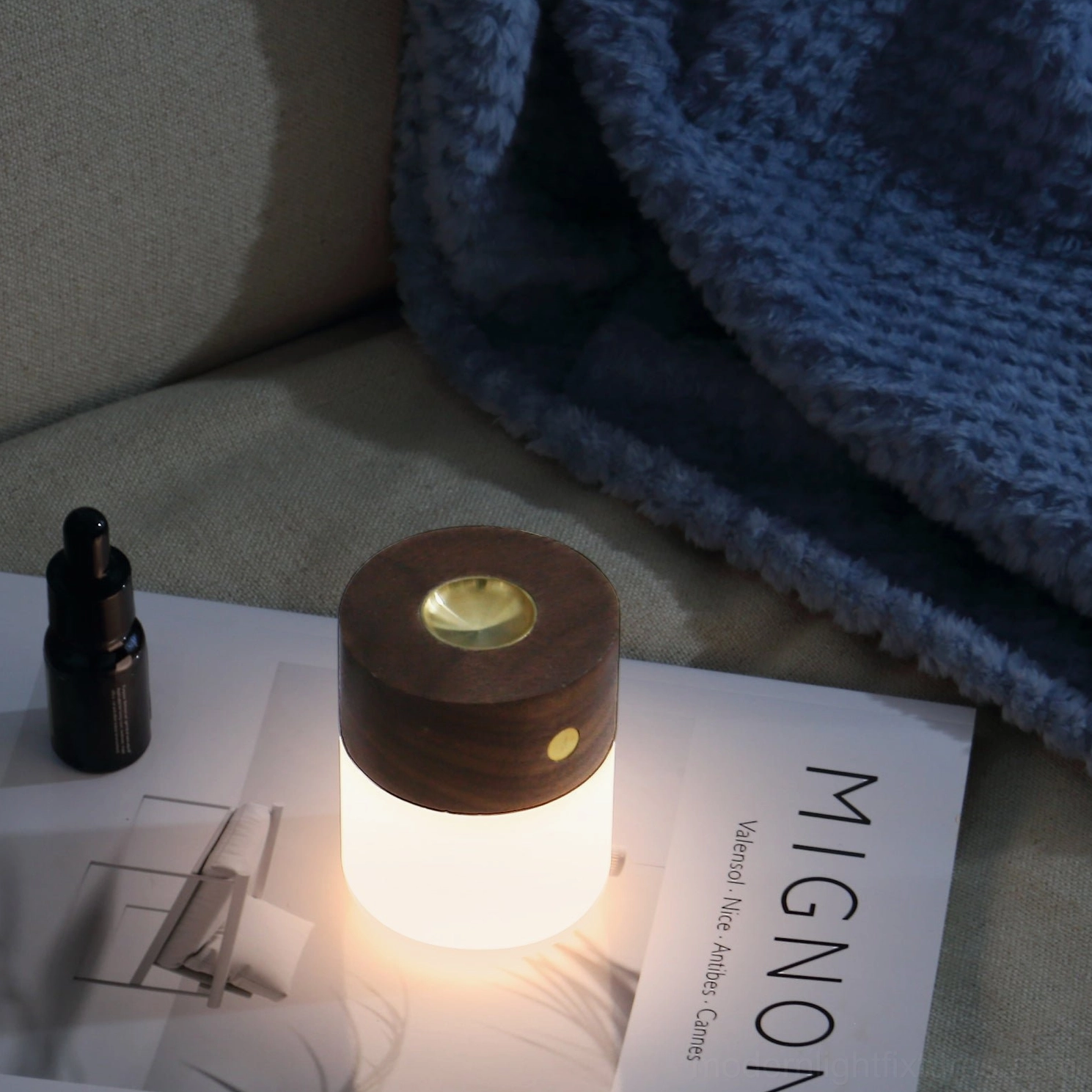 Lit aroma diffuser lamp with warm LED glow on living room side table with magazine styling