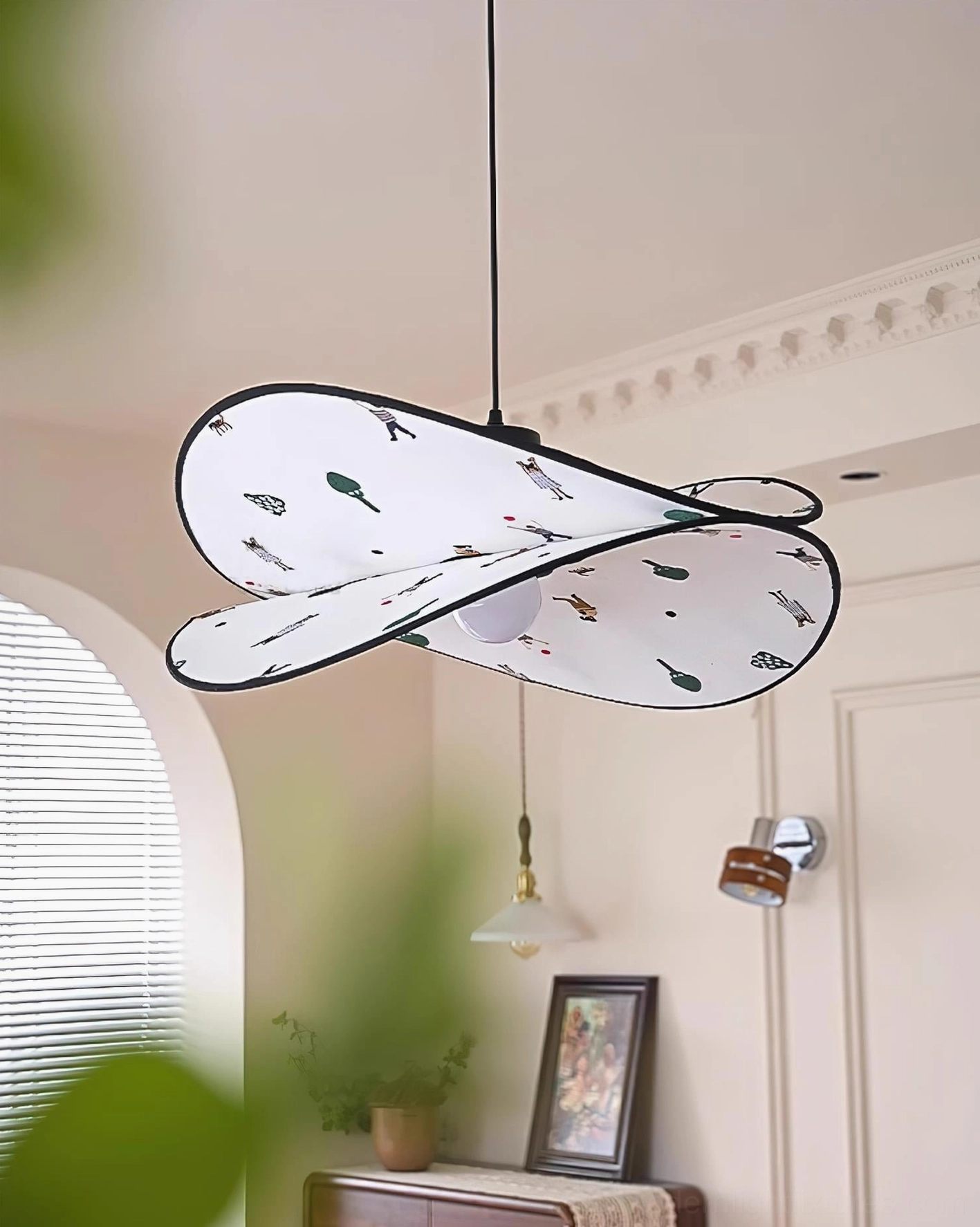 Dika pendant lamp casting warm ambient lighting, front low angle view in living room with potted plants