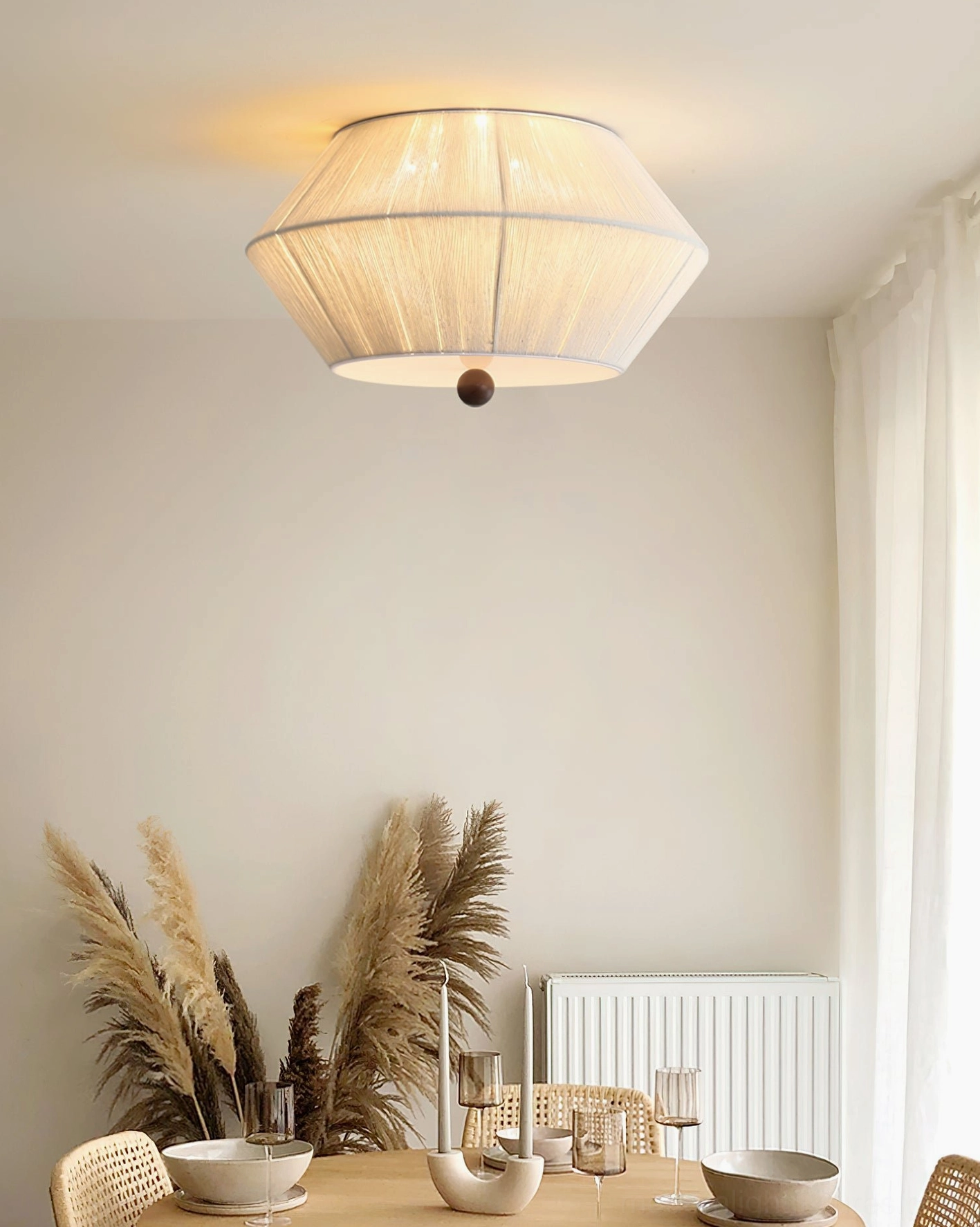 Tapered fabric flush mount light illuminating casual dining space with wooden table and warm neutral tones