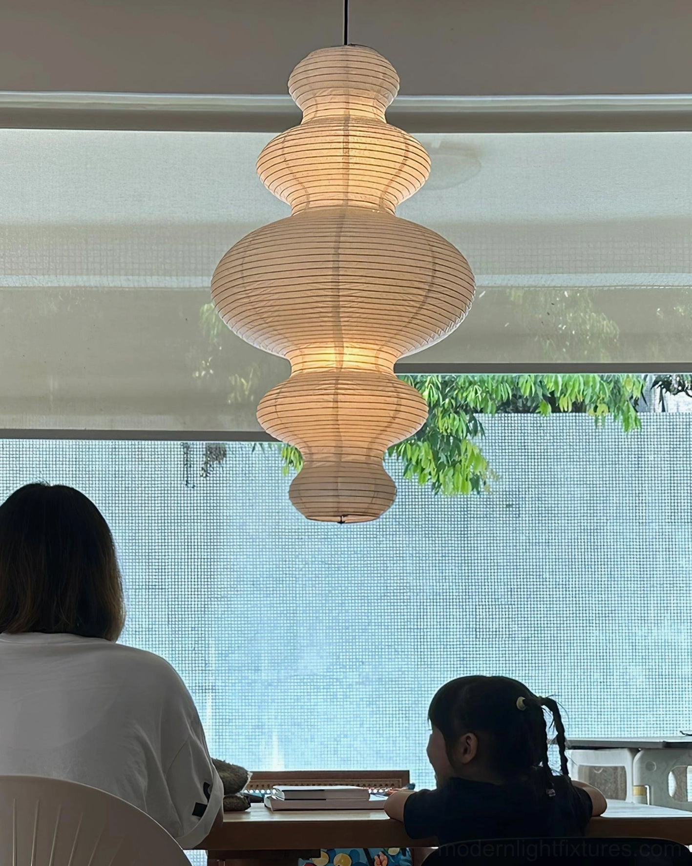 Hand-crafted rice paper pendant light in dining room ensuring soft equal illumination for all seated guests