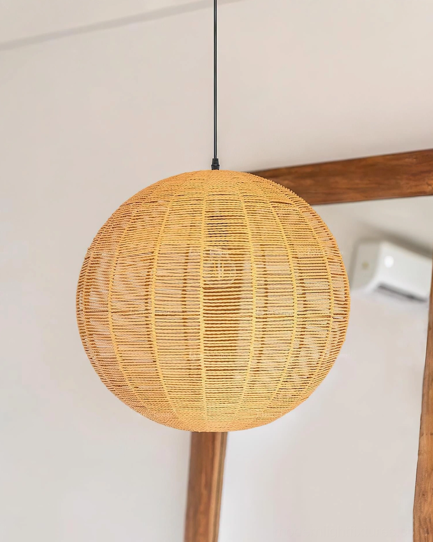 Rattan woven sphere pendant light installed above dining table with modern aesthetic