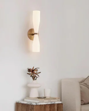 Side view of Diora wall sconce installed in contemporary living room, warm ambient lighting with brass mount and frosted glass