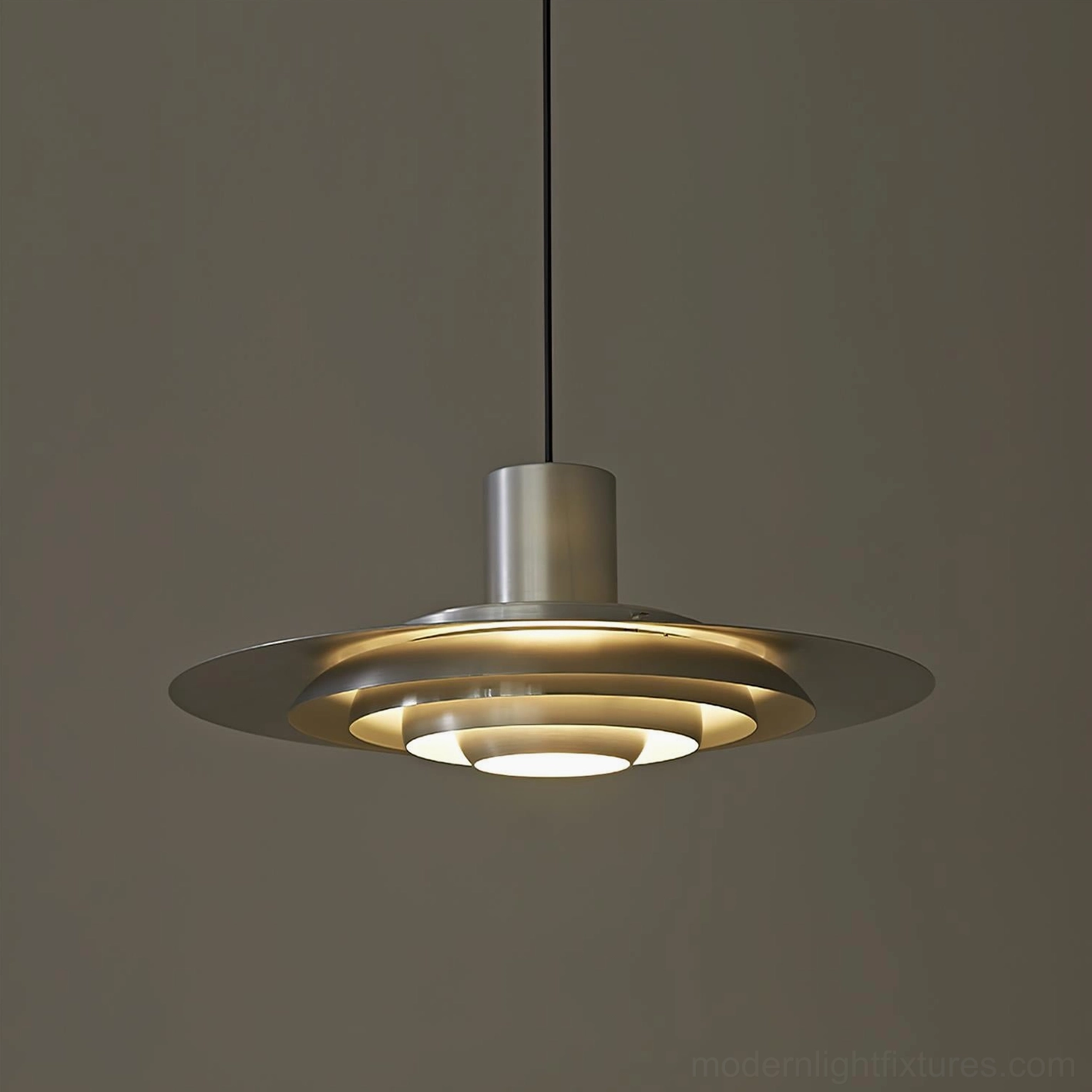 Layered disc pendant light close-up front view with warm glowing illumination, sleek metallic finish and diffused light quality