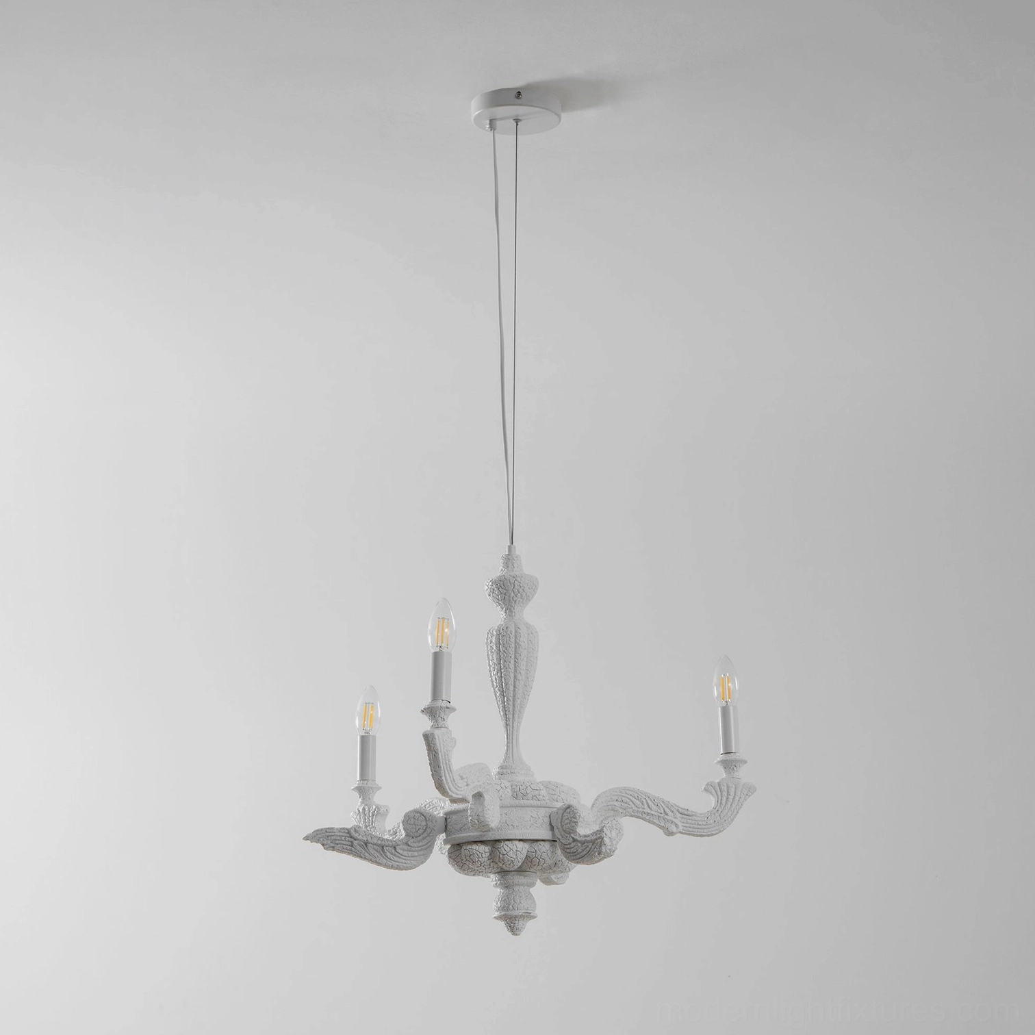 Distressed white sculptural four-arm candelabra chandelier with curved arms in studio lighting