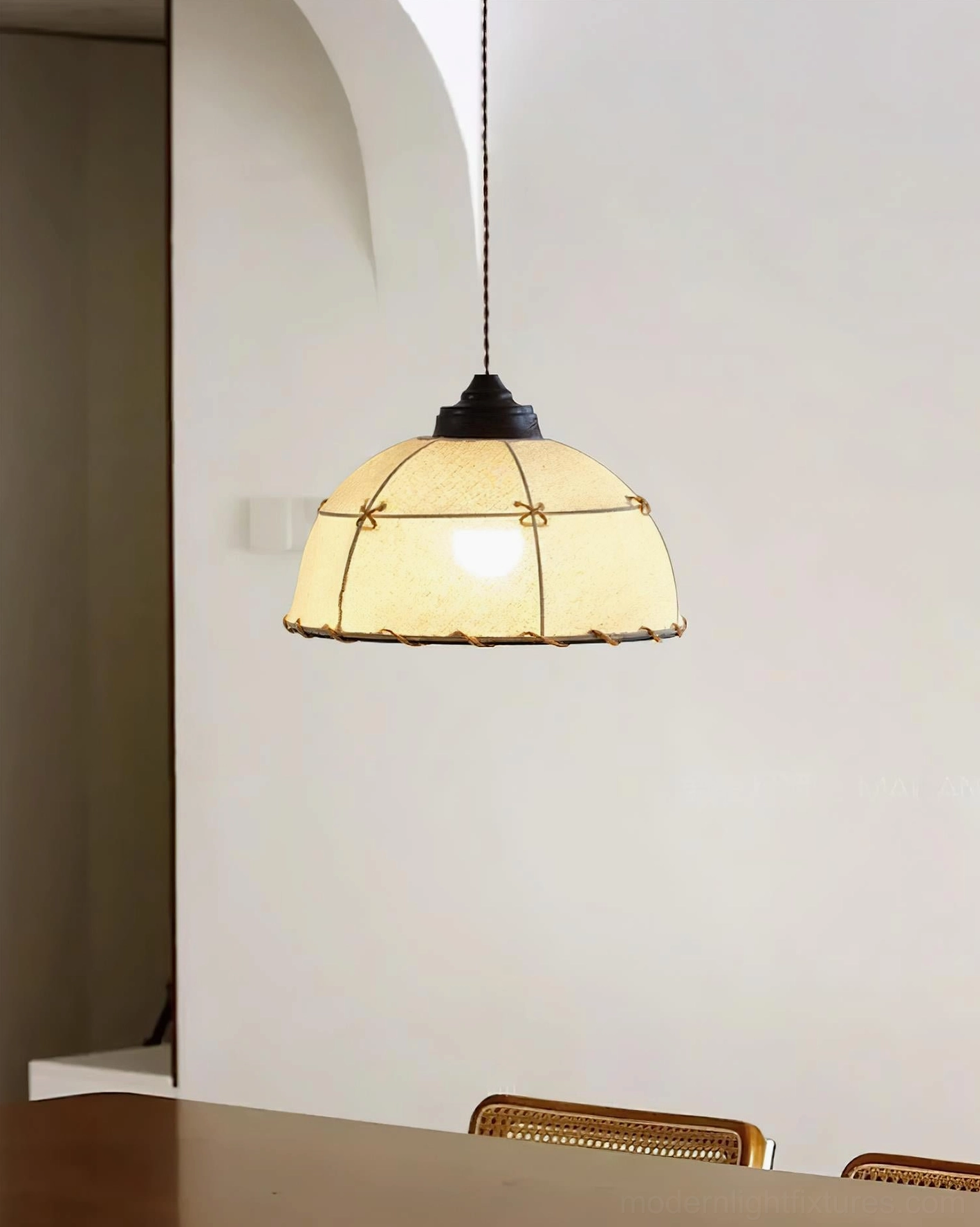 Handcrafted fabric pendant light illuminated over wooden dining table, beige canvas shade creating warm rustic lighting in retro interior setting with dining chairs