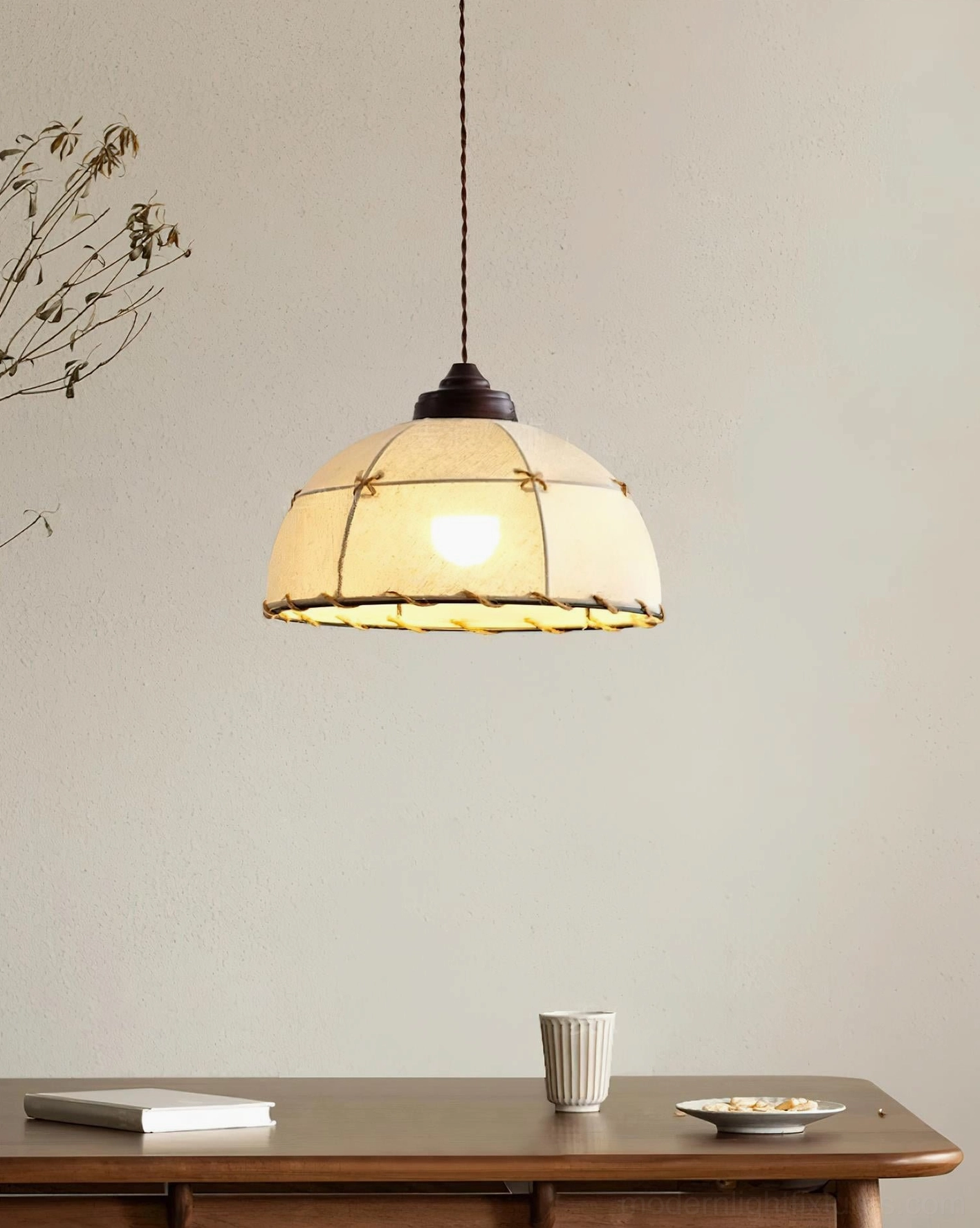 Walnut and white fabric pendant lamp illuminated above dining table in rustic wabi-sabi interior, warm ambient lighting with wooden dining furniture