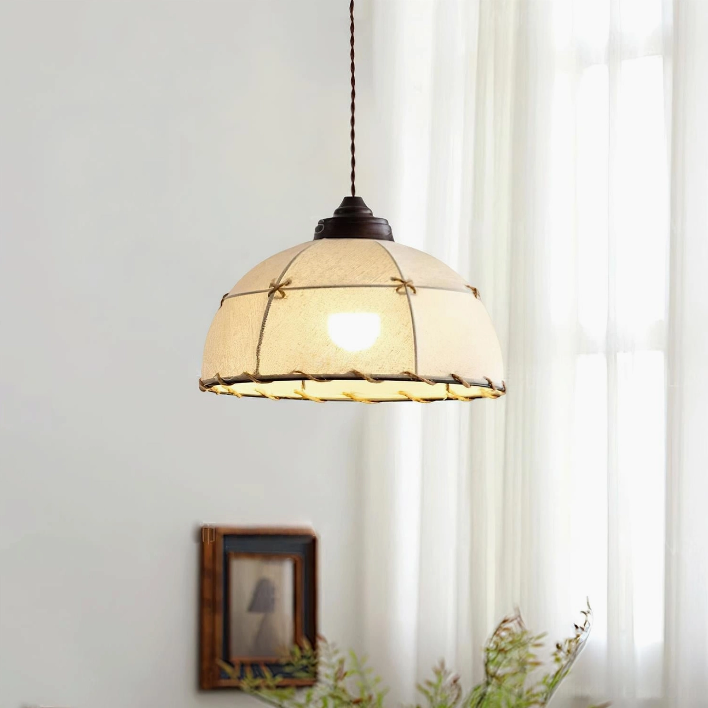 Dome Jari handcrafted pendant light in living room setting with wall artwork and green plants, braided rope grid decoration on beige fabric shade, warm rustic wabi-sabi style