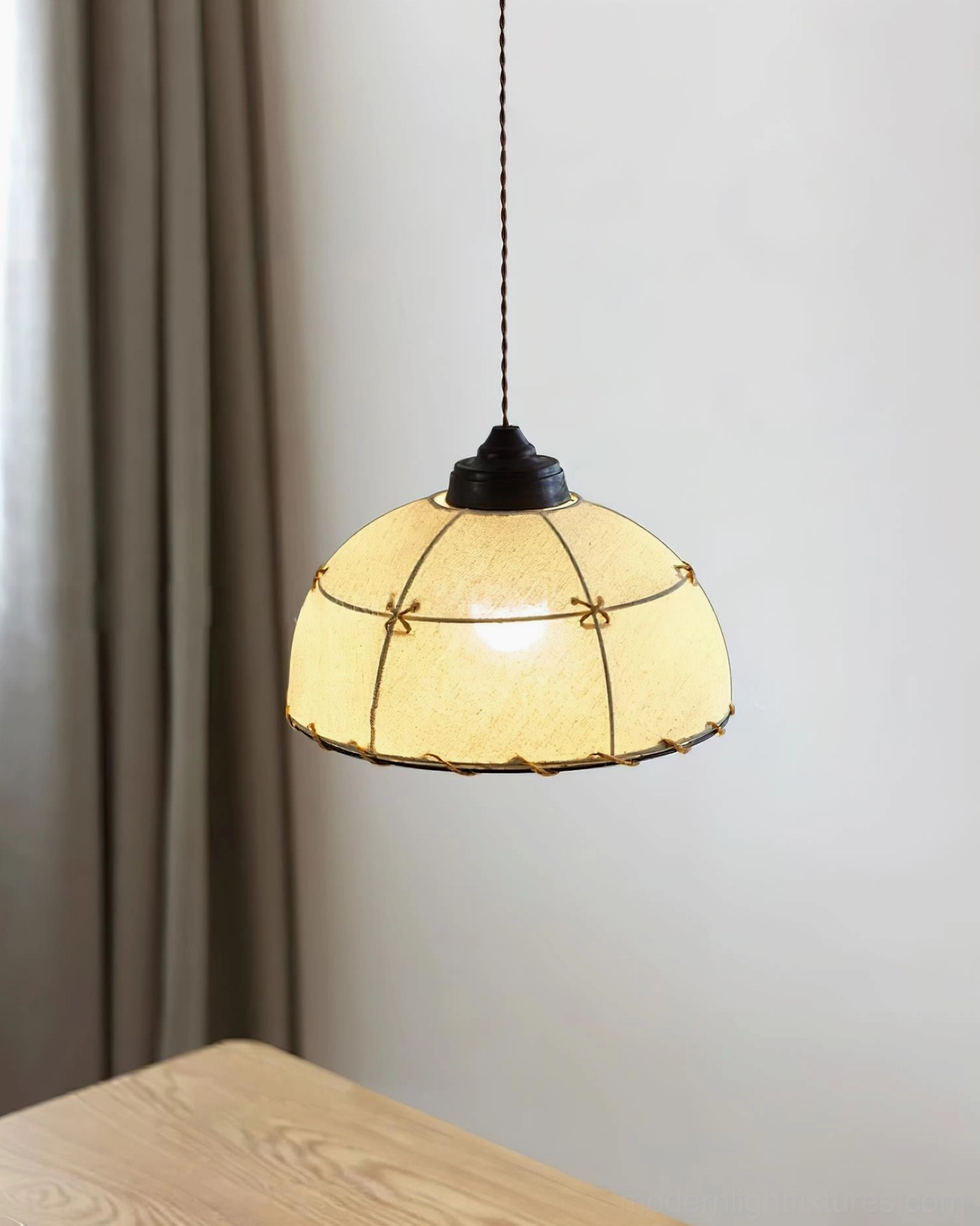 Fabric dome pendant lamp front hanging view with twisted brown suspension cord, warm diffused illumination against grey curtain and wooden furniture background
