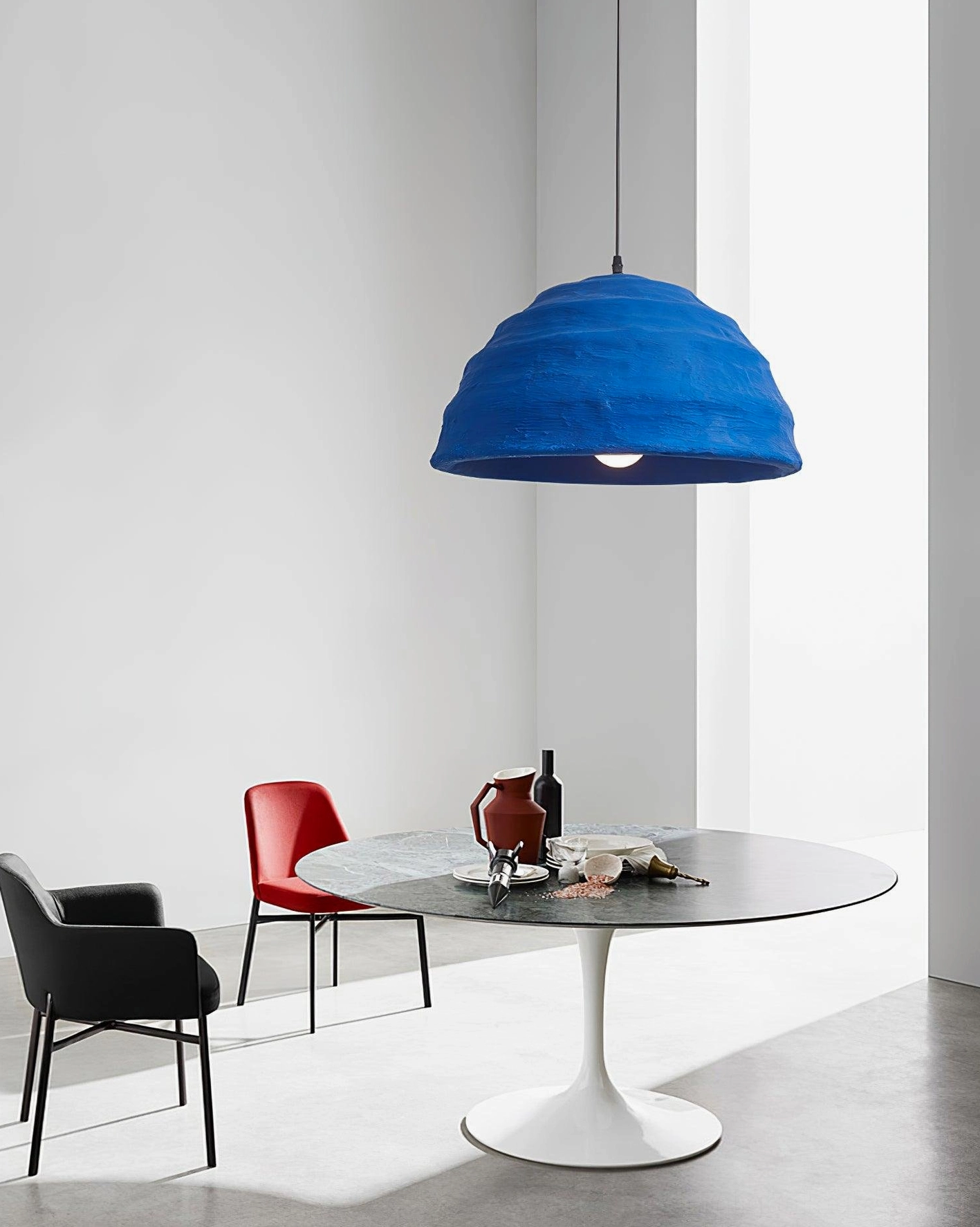 Side oblique view of azure dome pendant hanging above round marble dining table in minimalist dining room