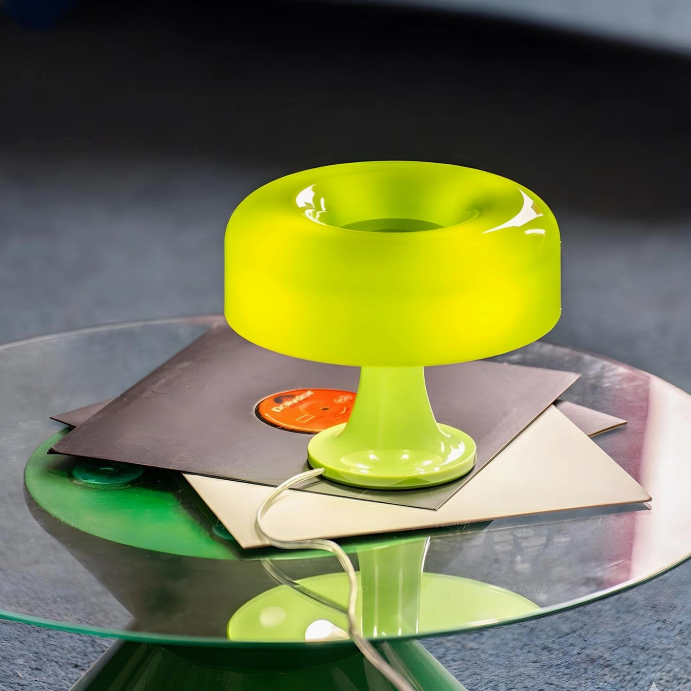 Lime green Donula donut table lamp illuminated on glass coffee table with vinyl records