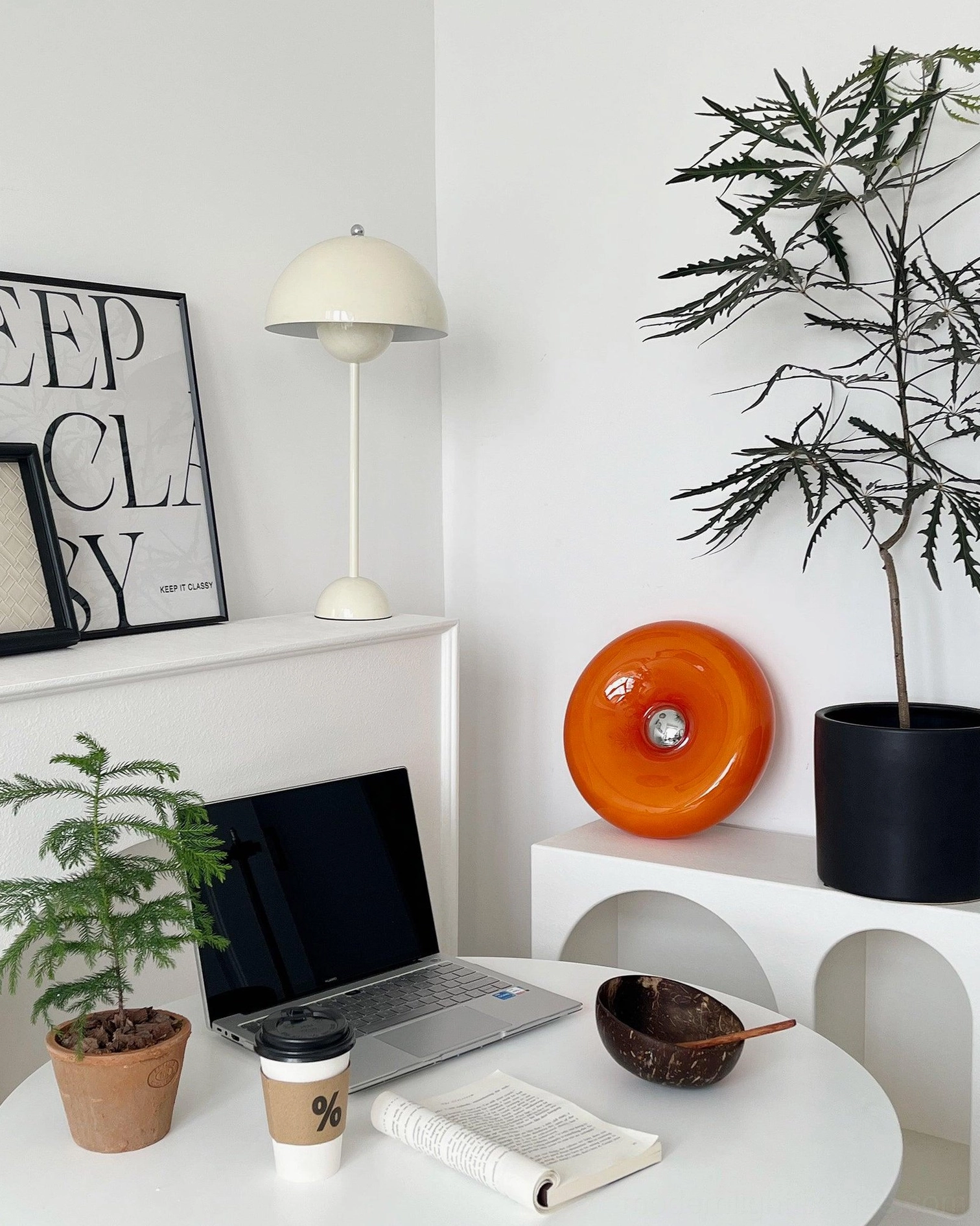 Donut table lamp placed on floating shelf in home office study with plants and wall art