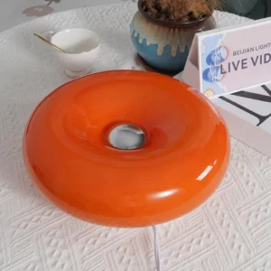 Orange donut shaped table lamp overhead view on decorated side table with power cord visible
