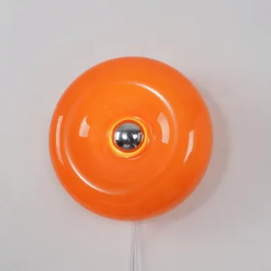 Retro orange donut wall lamp with white power cord and metallic socket, close-up studio shot
