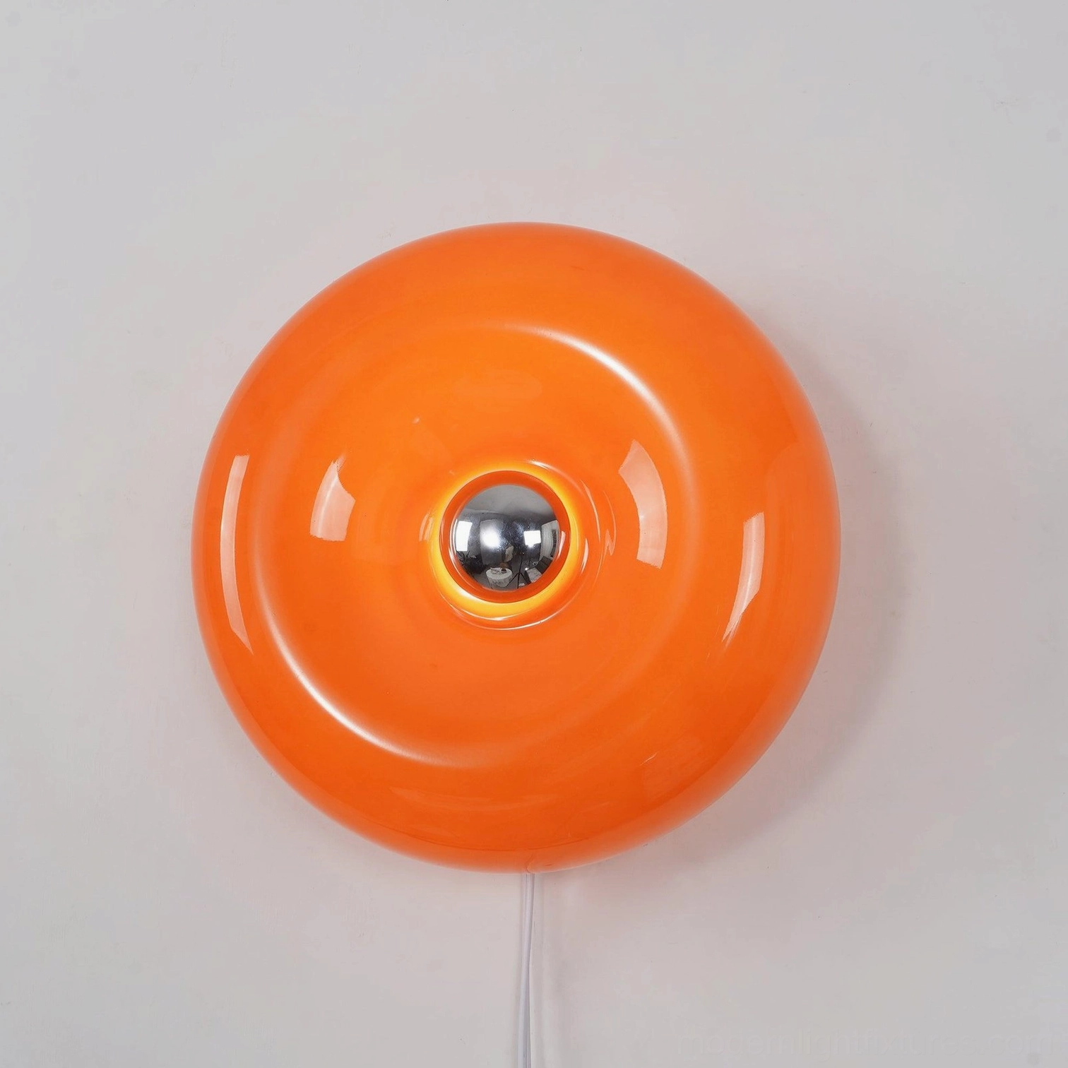 Retro orange donut wall lamp with white power cord and metallic socket, close-up studio shot