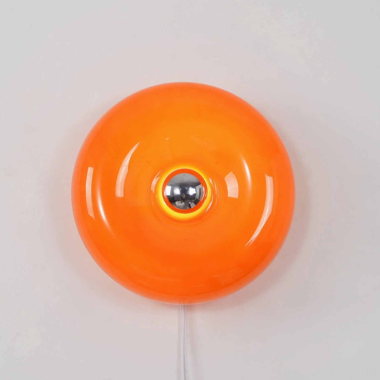 Orange donut wall light fixture with warm glow effect in studio setting with neutral background