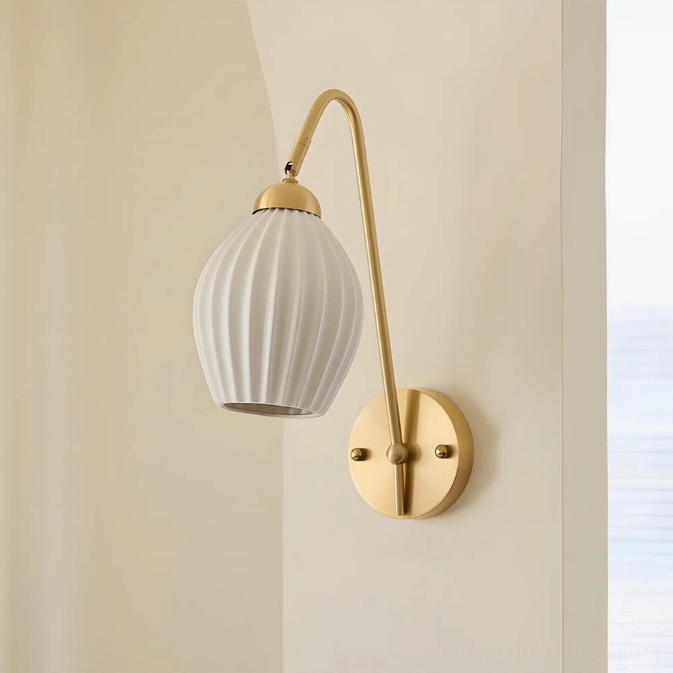 Dorelia brass wall sconce front product view with curved brass arm and round wall base on neutral background
