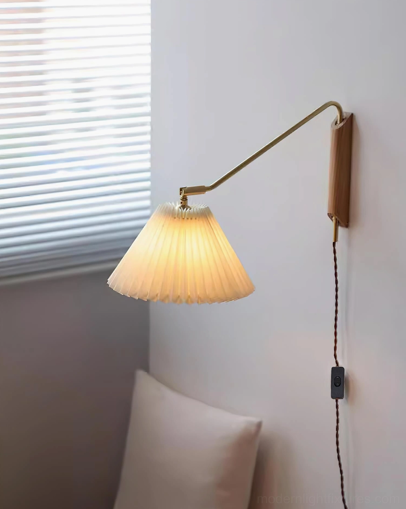 Dorset wall sconce in gold finish with pleated fabric shade mounted in modern space