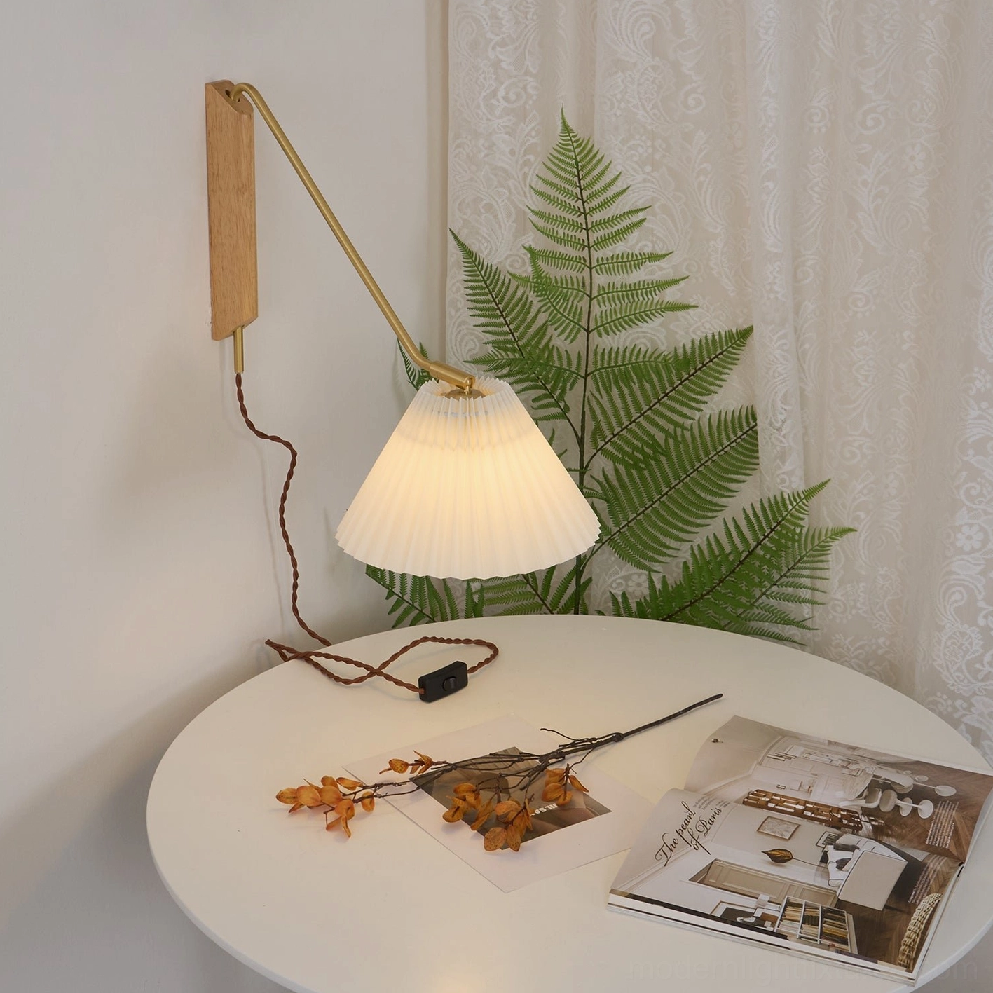 Dorset wall sconce installed above round dining table with brass arm extended position