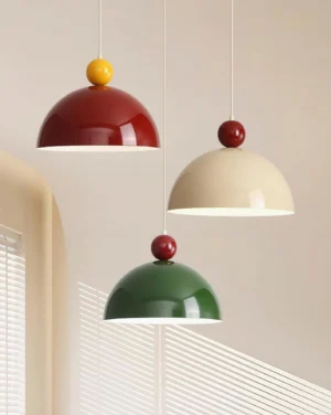Set of three Dotto color-block pendant lights in burgundy-cream and green, installed in warm residential dining interior with ambient lighting