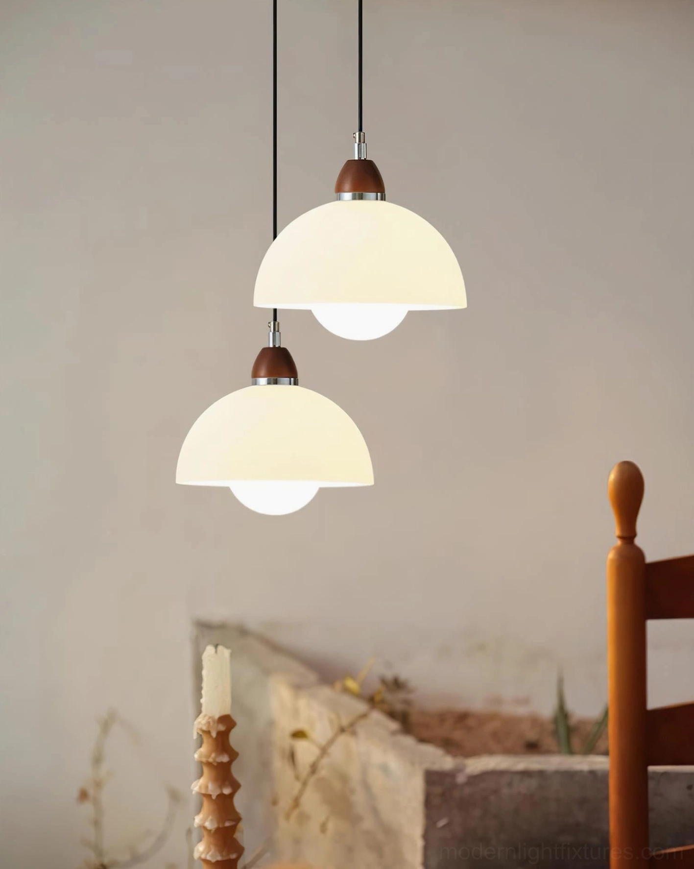 Two hanging domed pendant lights in vintage dining setting, cream-white matte shades with warm glowing illumination