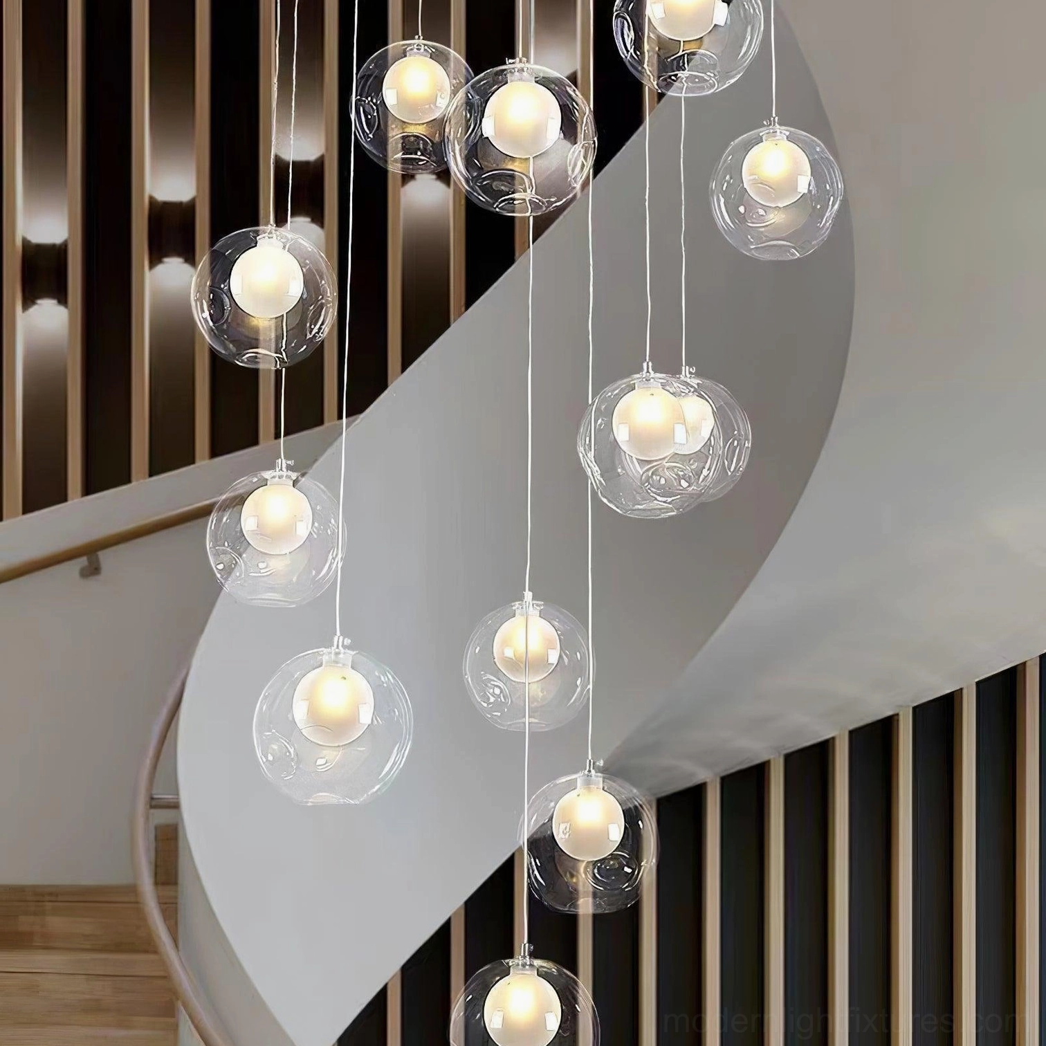 Double-layer glass globe stairwell pendant chandelier with clear glass clusters and warm ambient lighting in residential curved stairwell