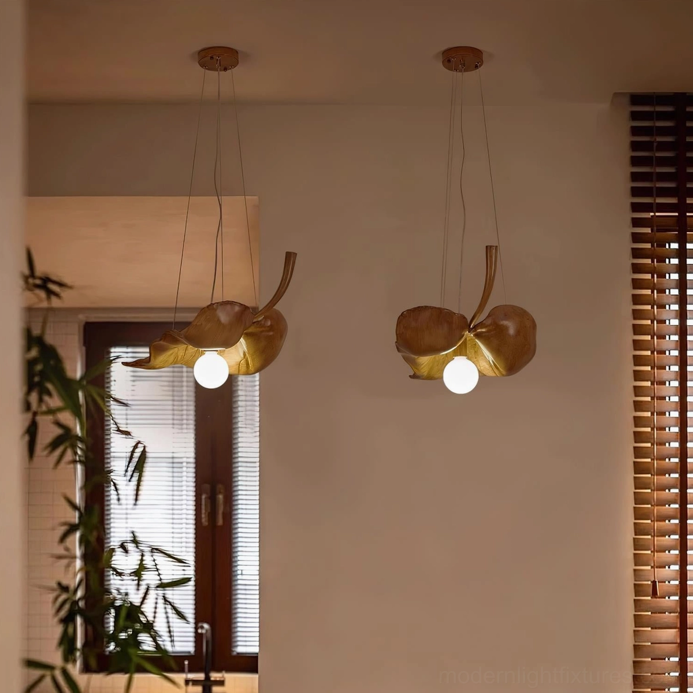 Dual matching maple leaf pendant lights in brown wood tone hanging in living room with windows and plants