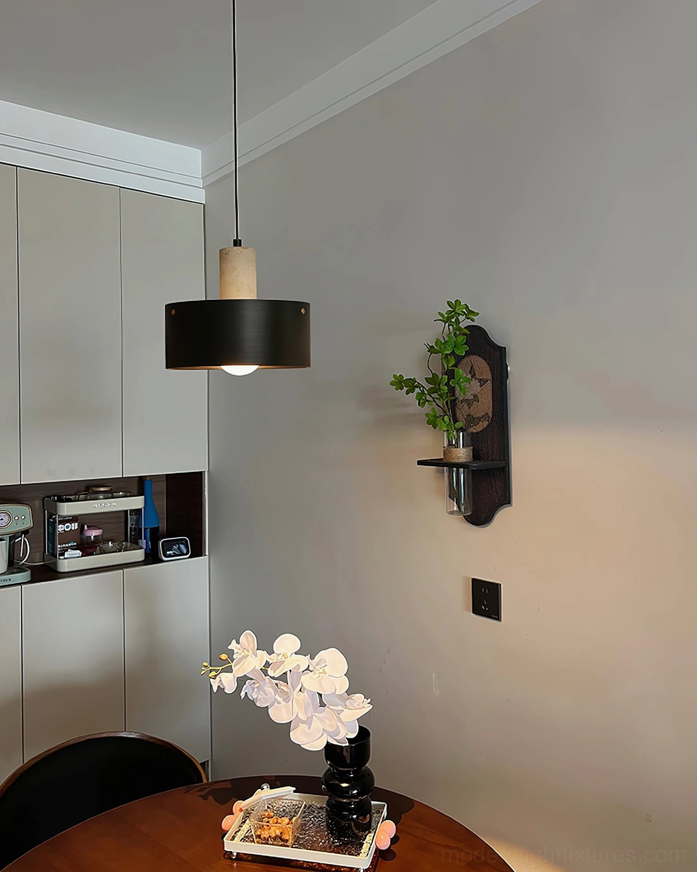 Black Dovira drum pendant light suspended in vintage kitchen dining space with wall-mounted plant shelf and warm retro atmosphere