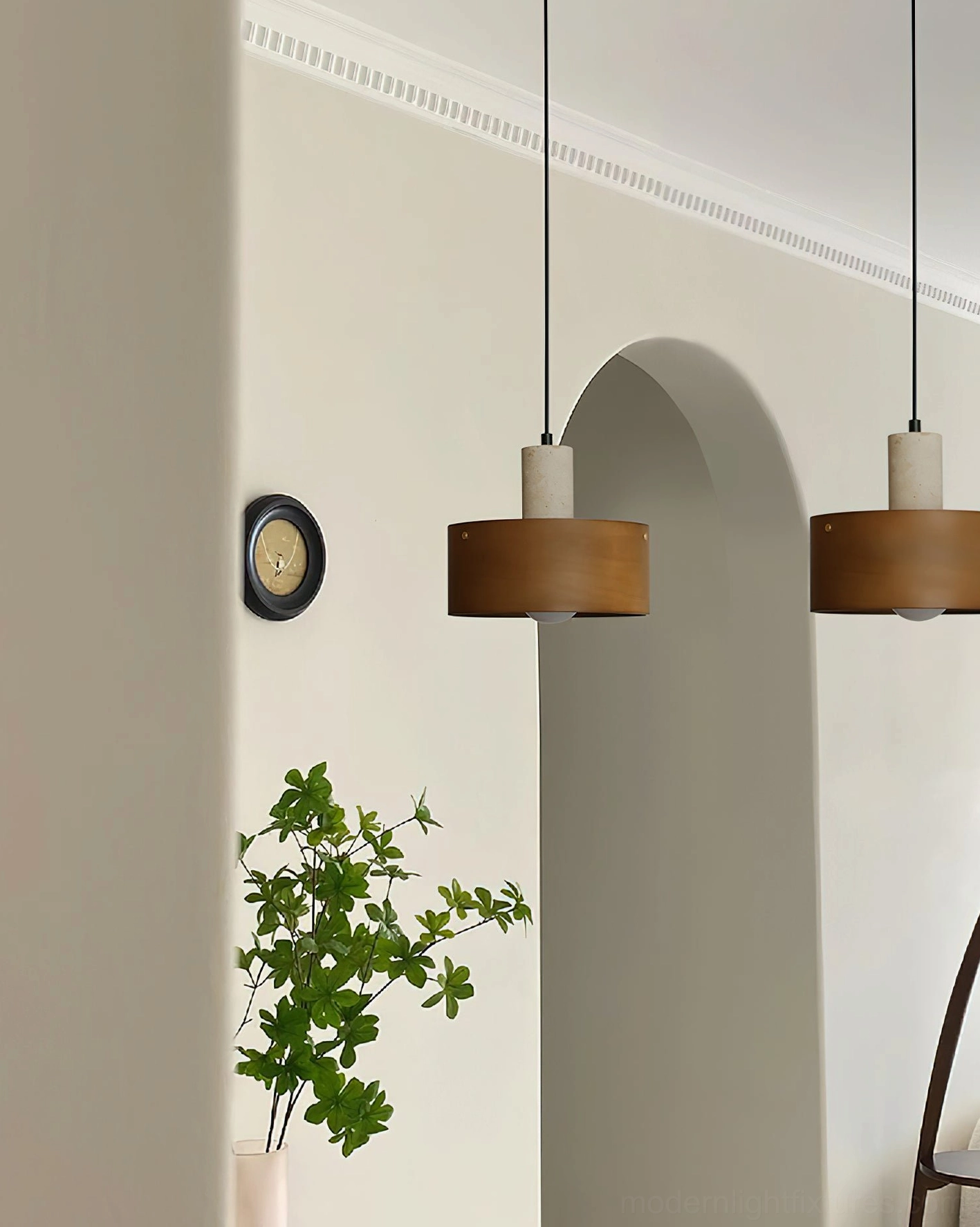 Two wooden Dovira drum pendant lights in residential hallway with arched architectural ceiling details, green plant styling, and warm minimalist aesthetic