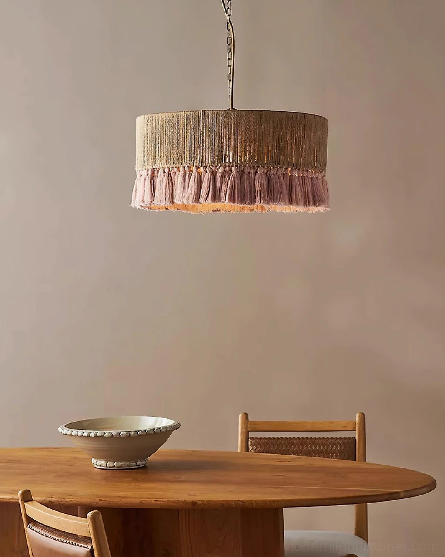 Drum pendant lamp with dusty pink tassel trim in dining room with wooden table