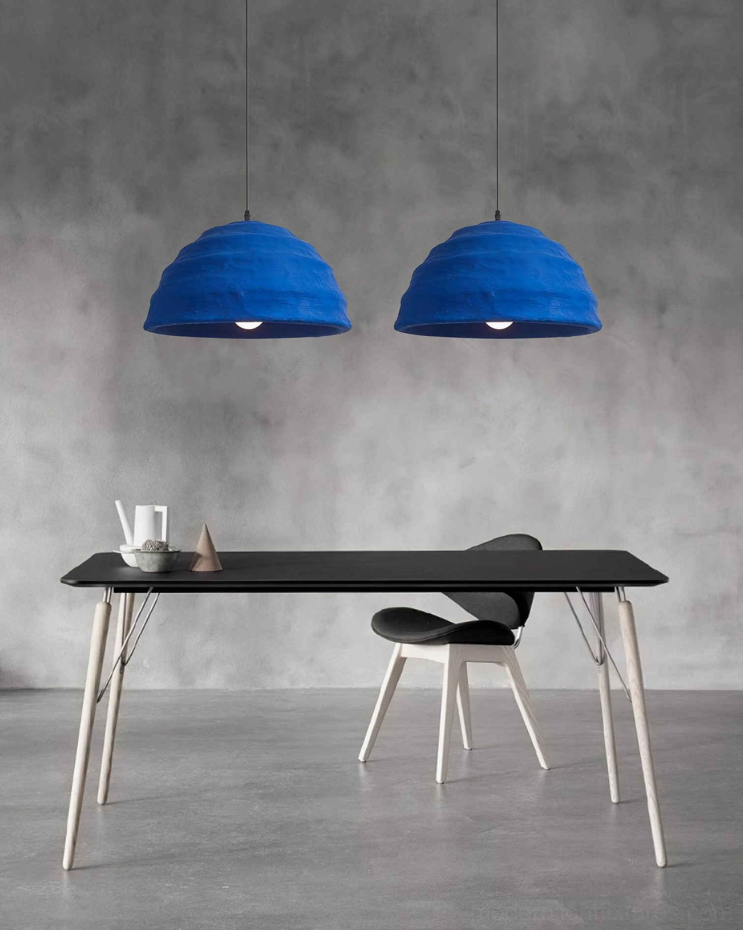 Twin azure dome pendant lamps suspended above black dining table in industrial minimalist dining space