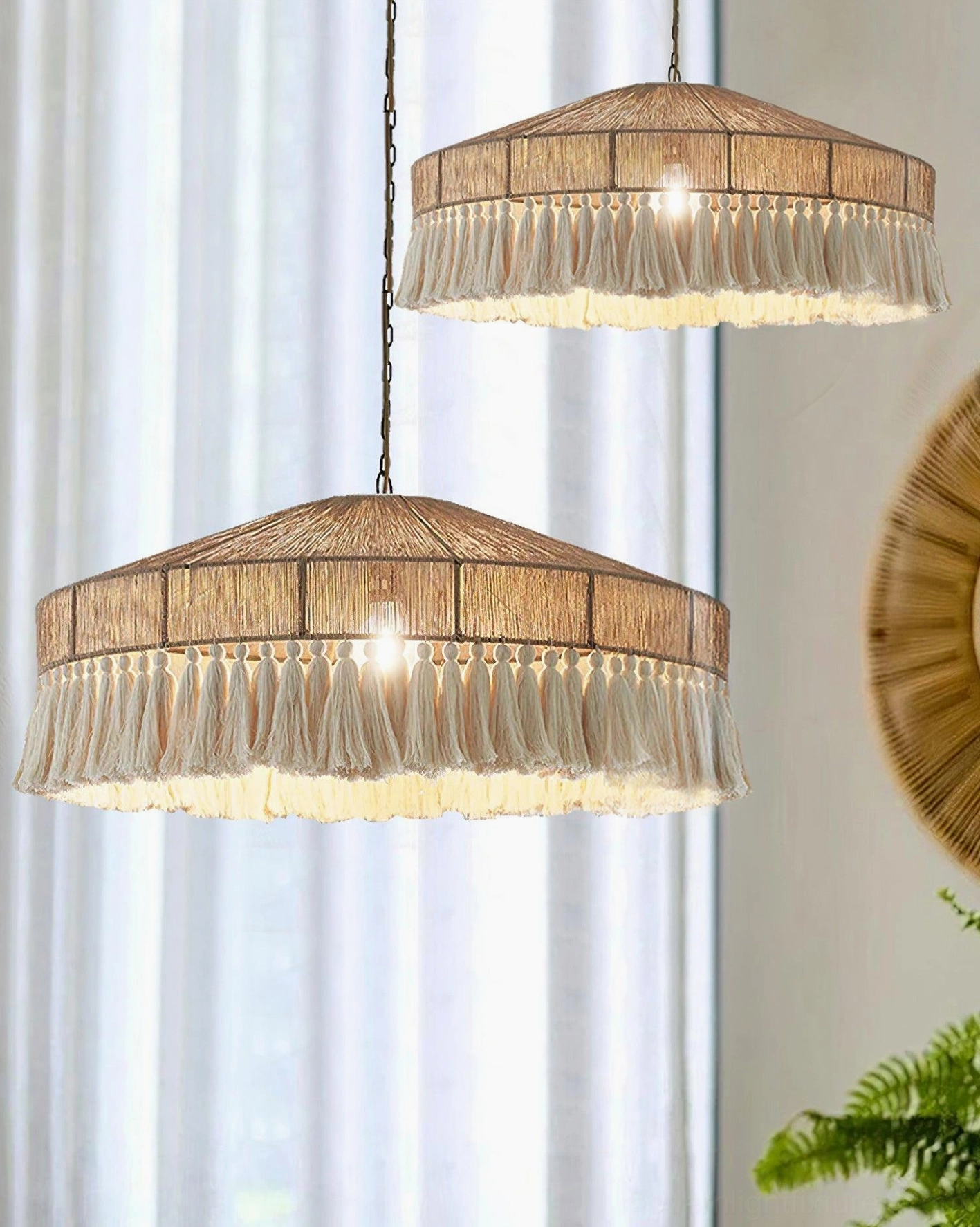Pair of matching bohemian fringe tassel pendant lamps hanging side by side in sunlit room with sheer window curtains, demonstrating cozy boho home styling aesthetic