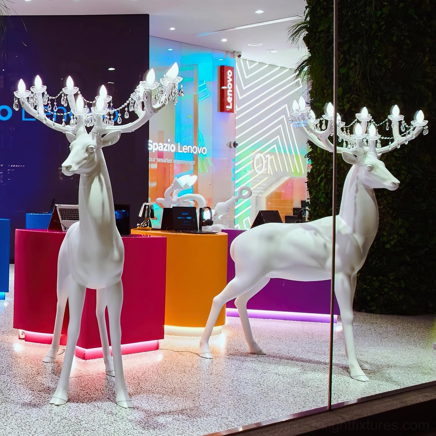 Pair of white matte deer sculpture floor lamps with chandelier antlers viewed through retail display window