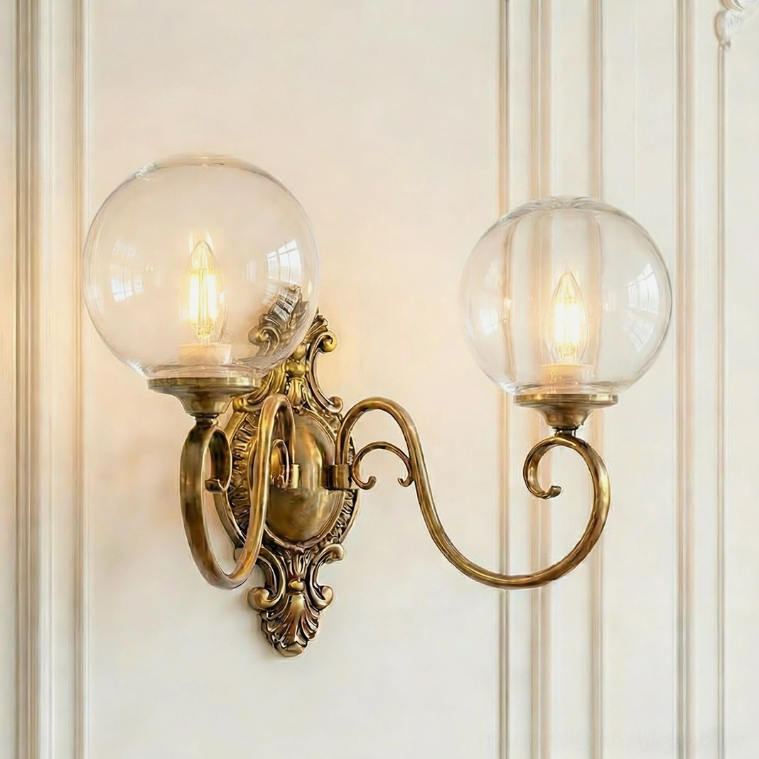 Dual-head ornate brass wall sconce with clear glass globes, baroque backplate dual-arm design